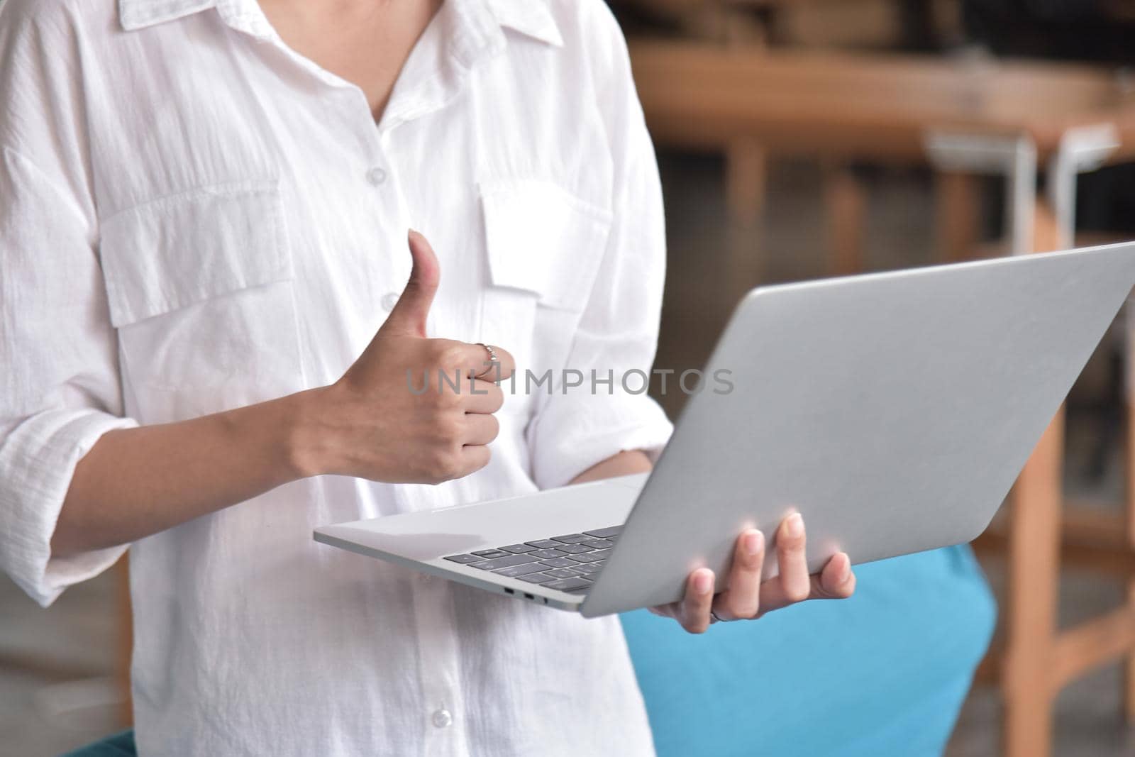 Young woman useing and holding silver laptop at the workplace, closeup