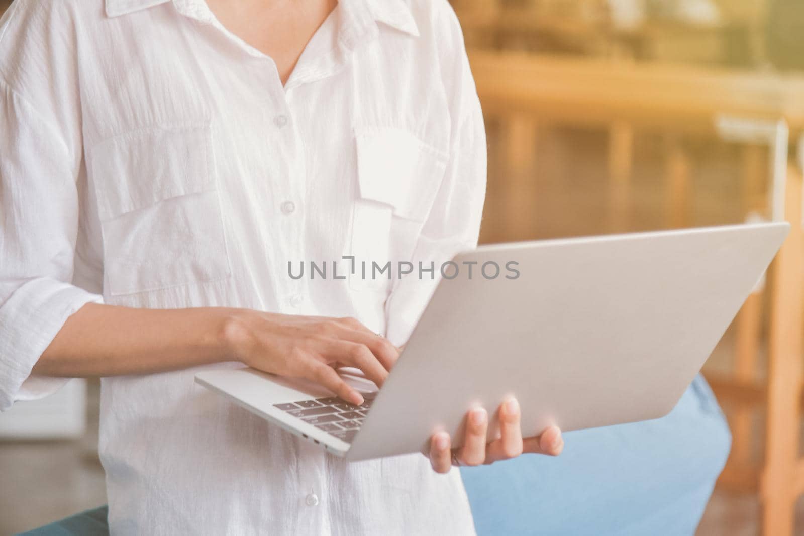 Young woman useing and holding silver laptop at the workplace, closeup