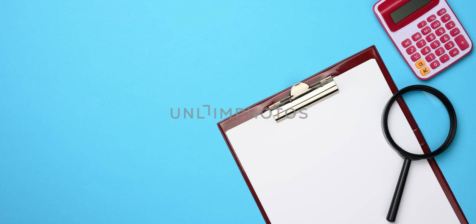 pink calculator, folder with blank white sheets and black magnifier on a blue background. Banner for business, top view