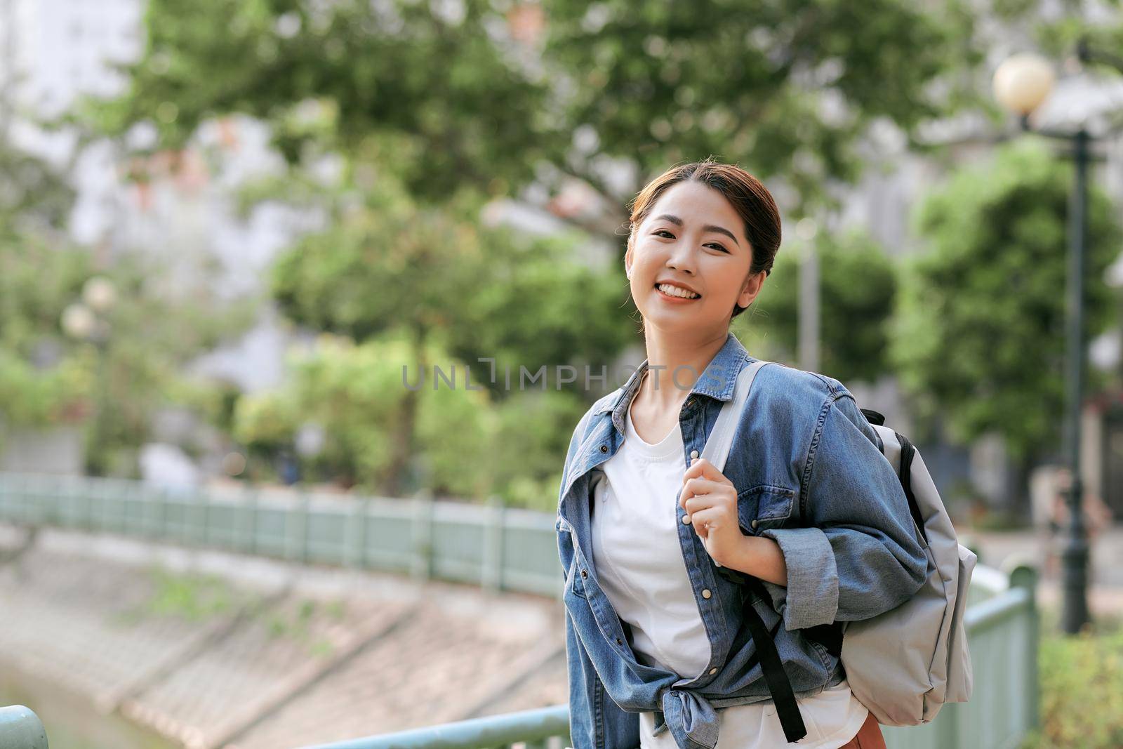 Portrait of young stylish woman walking on the street, wearing cute trendy outfit, smiling enjoy her weekends, travel with backpack