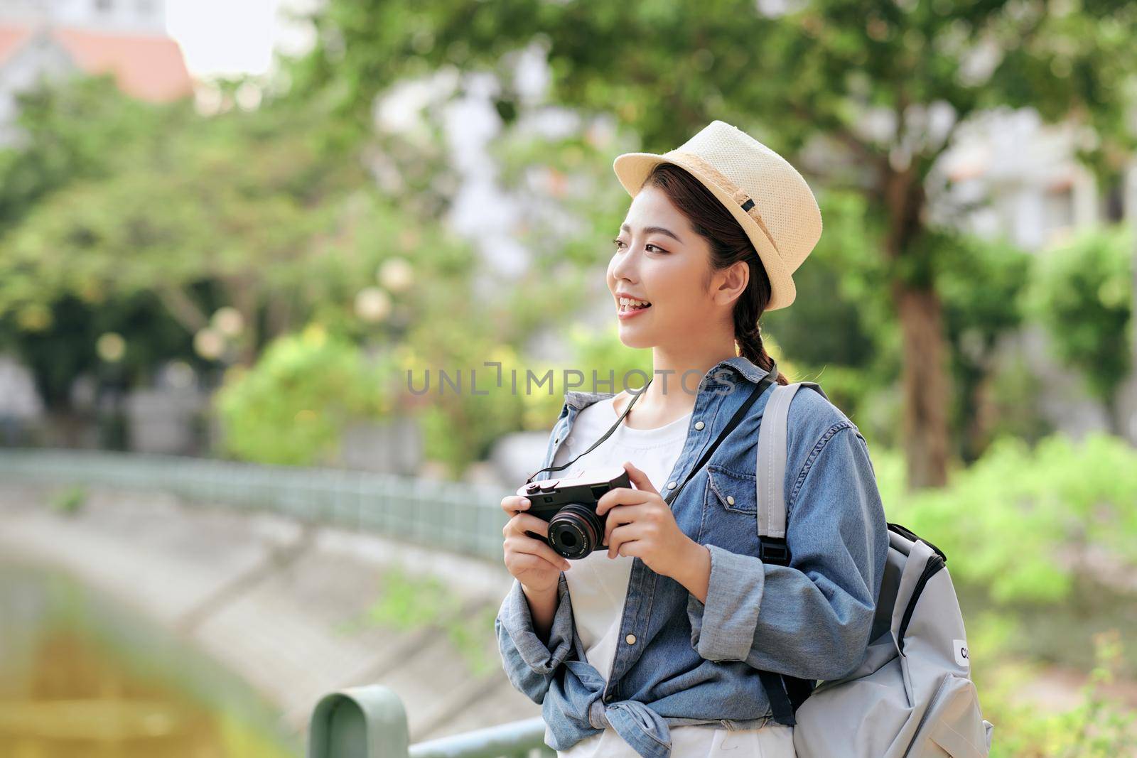Young pretty cheerful girl posing on the street at sunny day, having fun alone, young photographer with vintage camera.