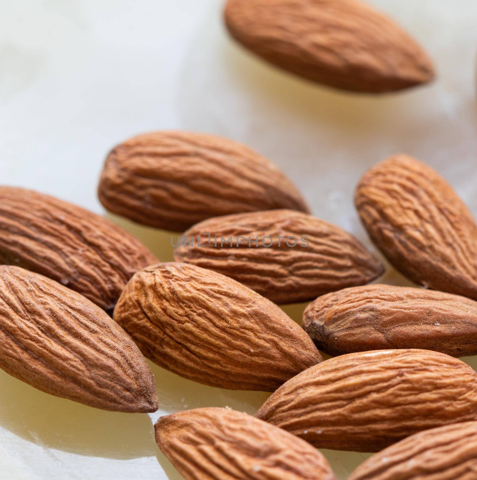 Almonds close-up on white onyx marble background.