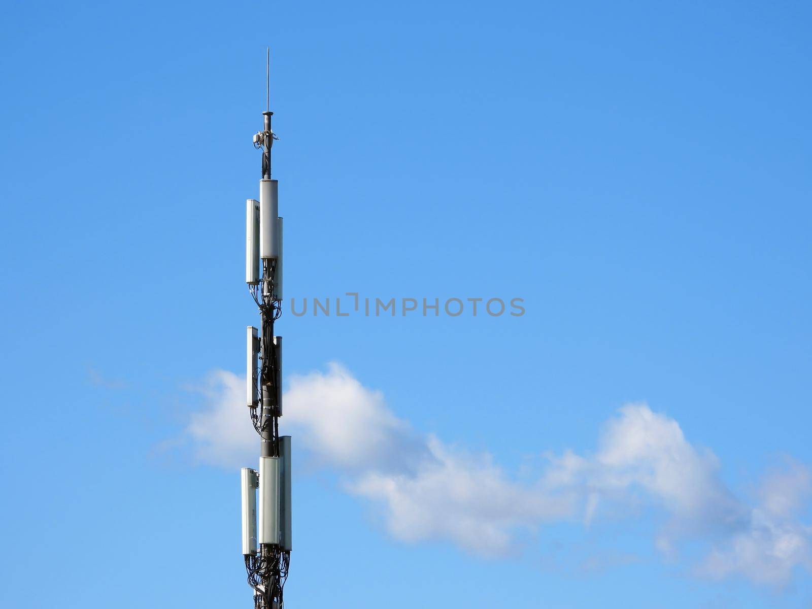 Cellular tower on the blue sky with some clouds background