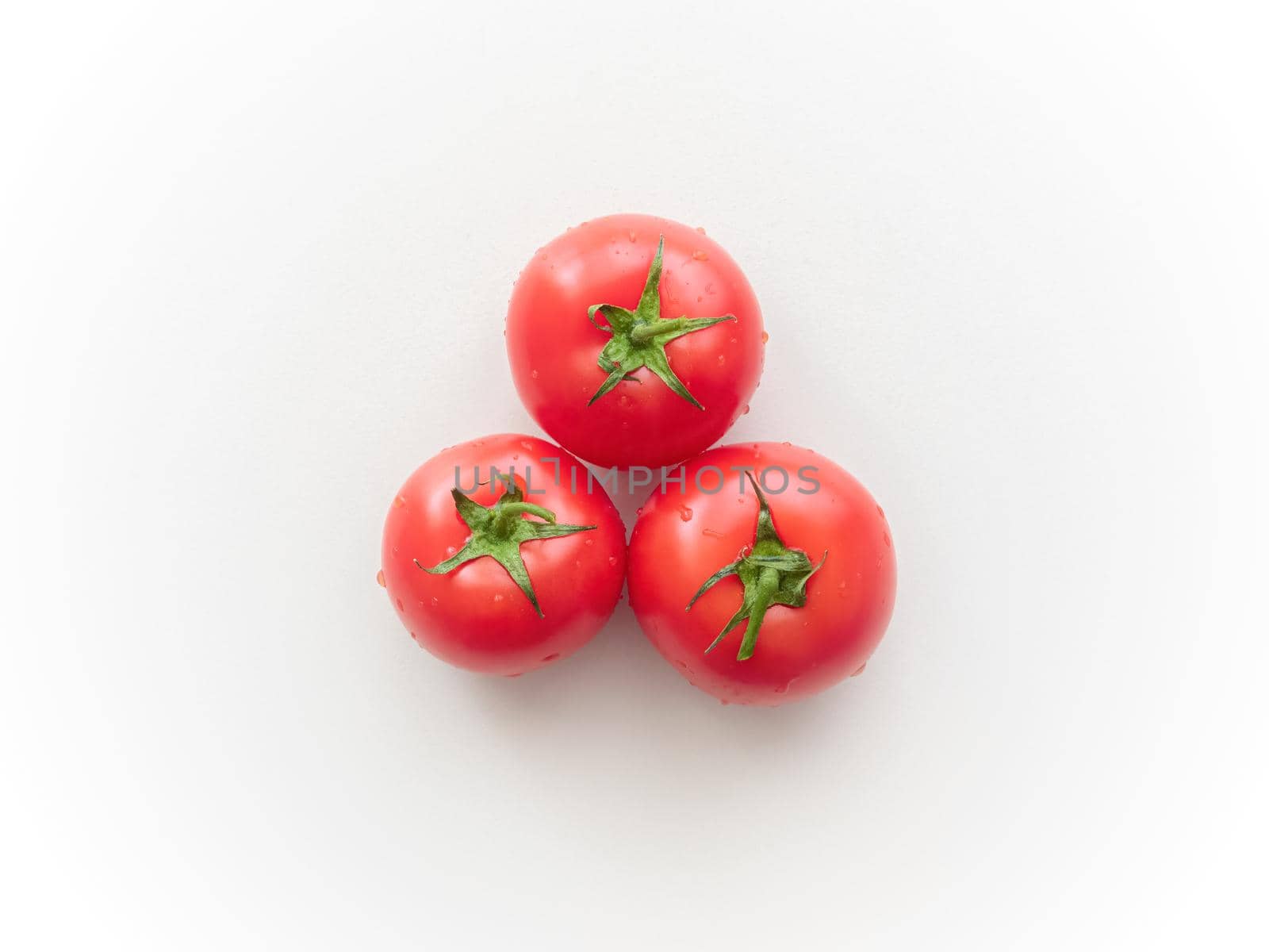 Three ripe tomatoes on a light gray ceramic surface. Top view. Not isolated