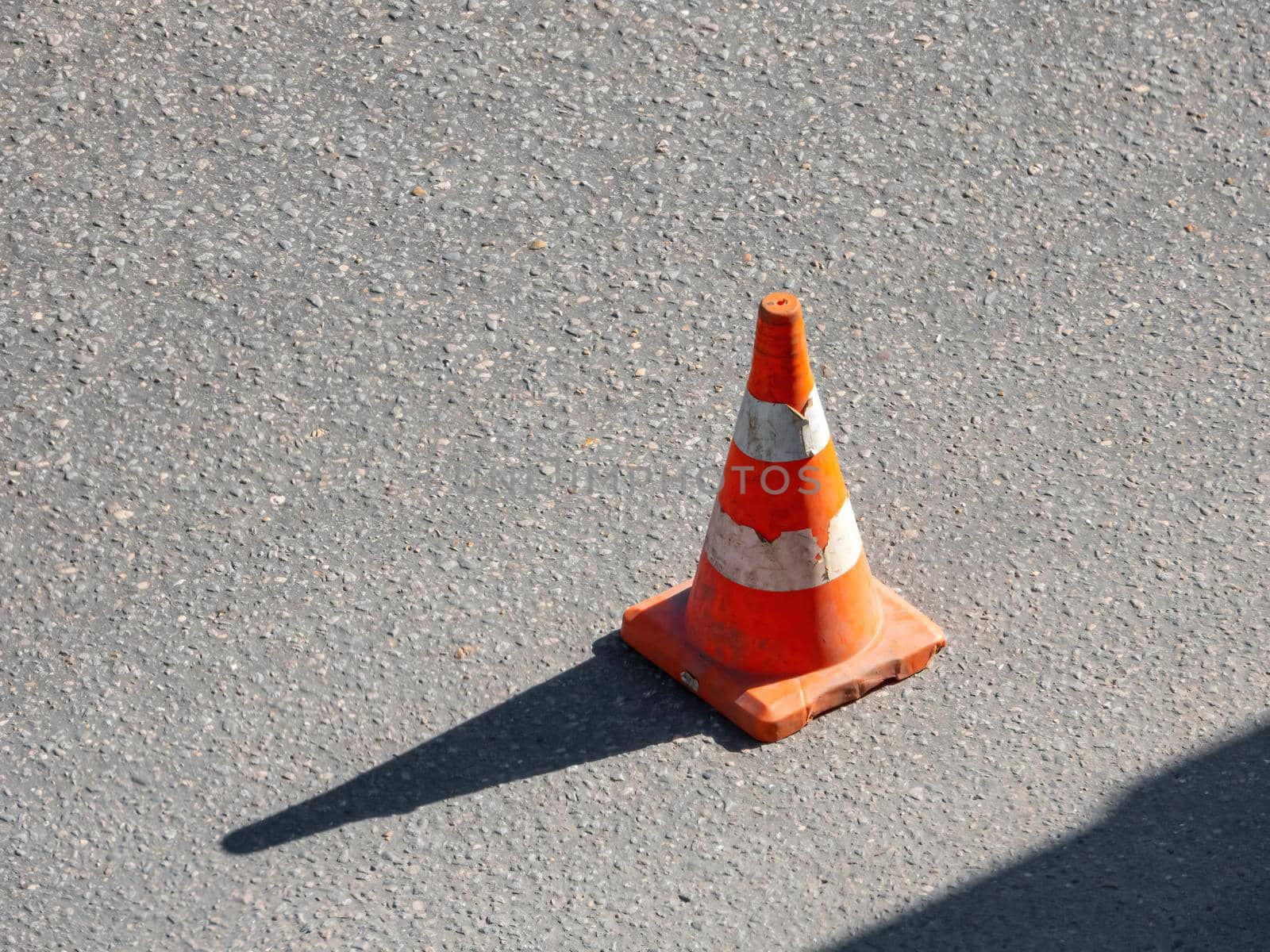 Old traffic cone standing on the asphalt road