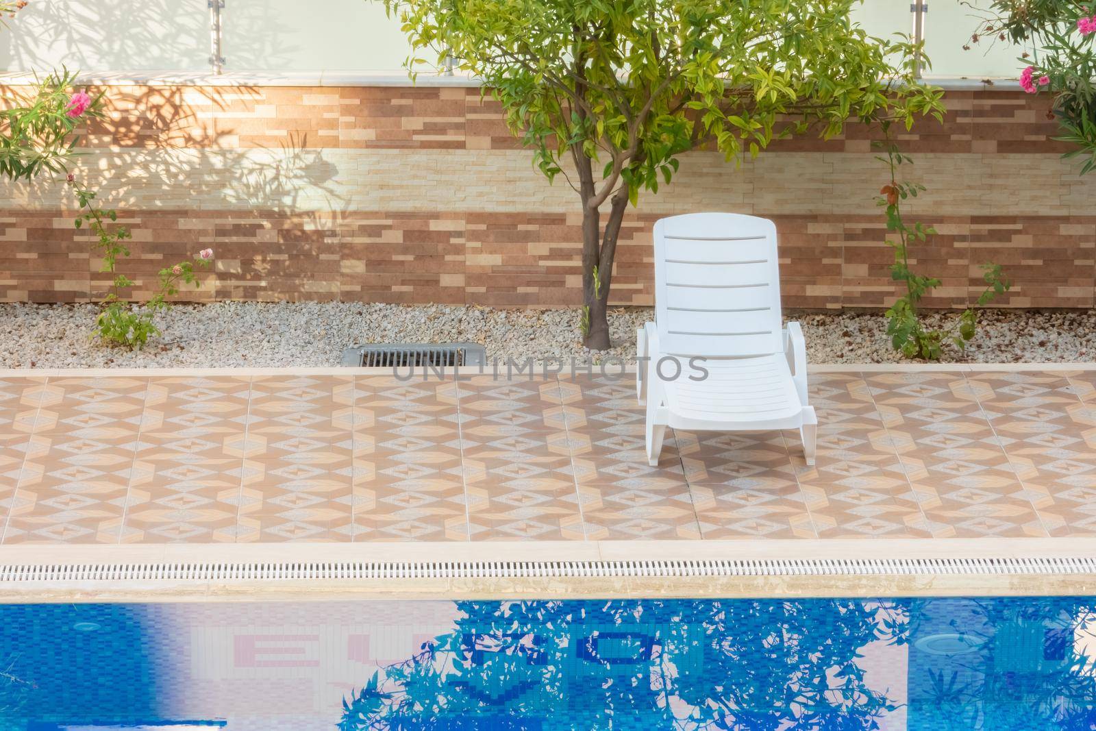 Empty white plastic sun lounger nearby the pool on a summer morning. Alanya, Turkey - August 24, 2020