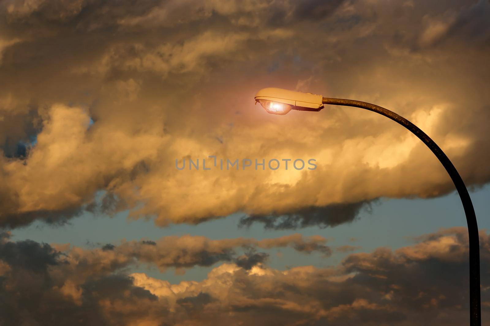 Street lamp lit with storm clouds in the background.