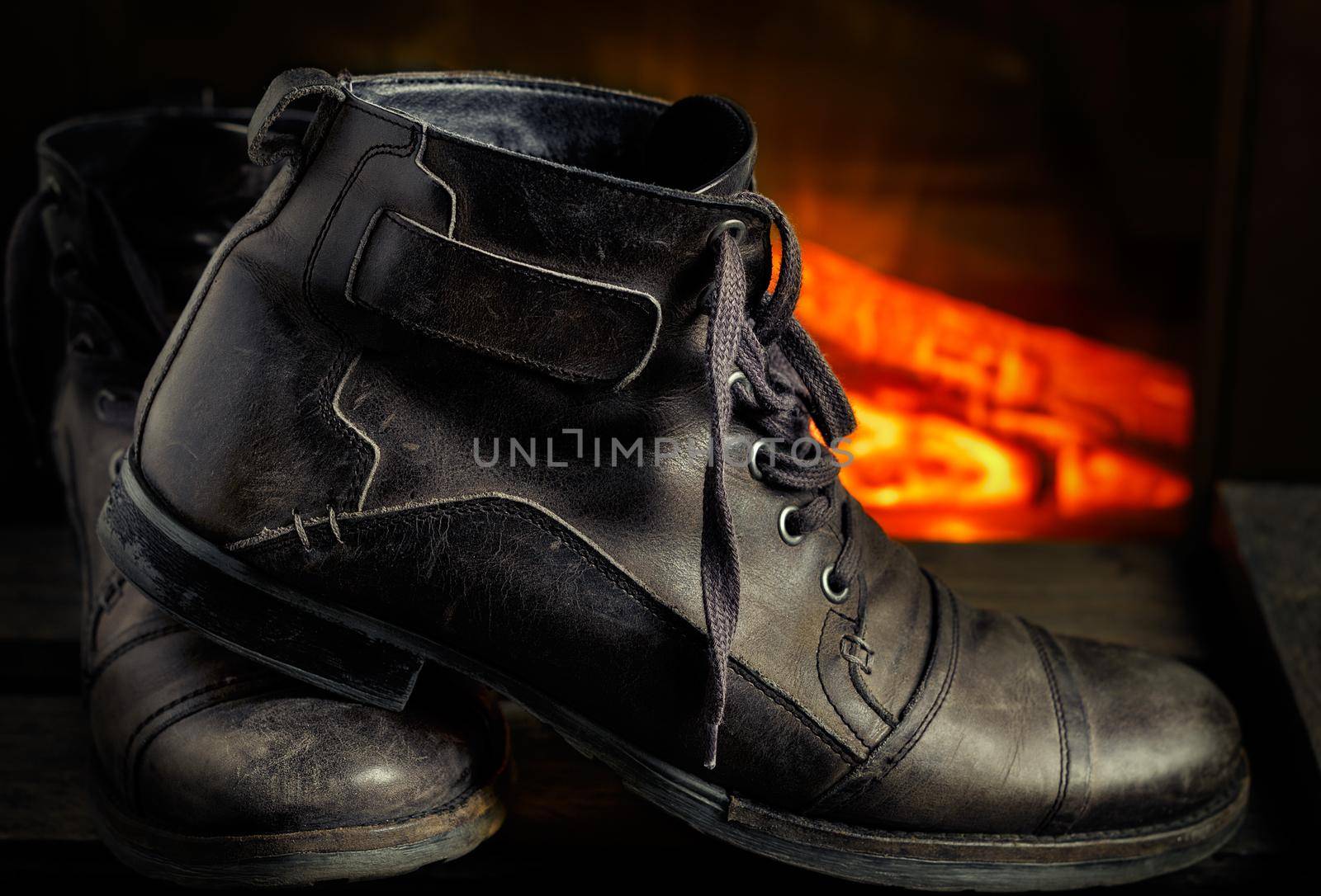 Casual gray leather shoes for men on wooden board with fireplace in the background. Dark mood style. Horizontal image.