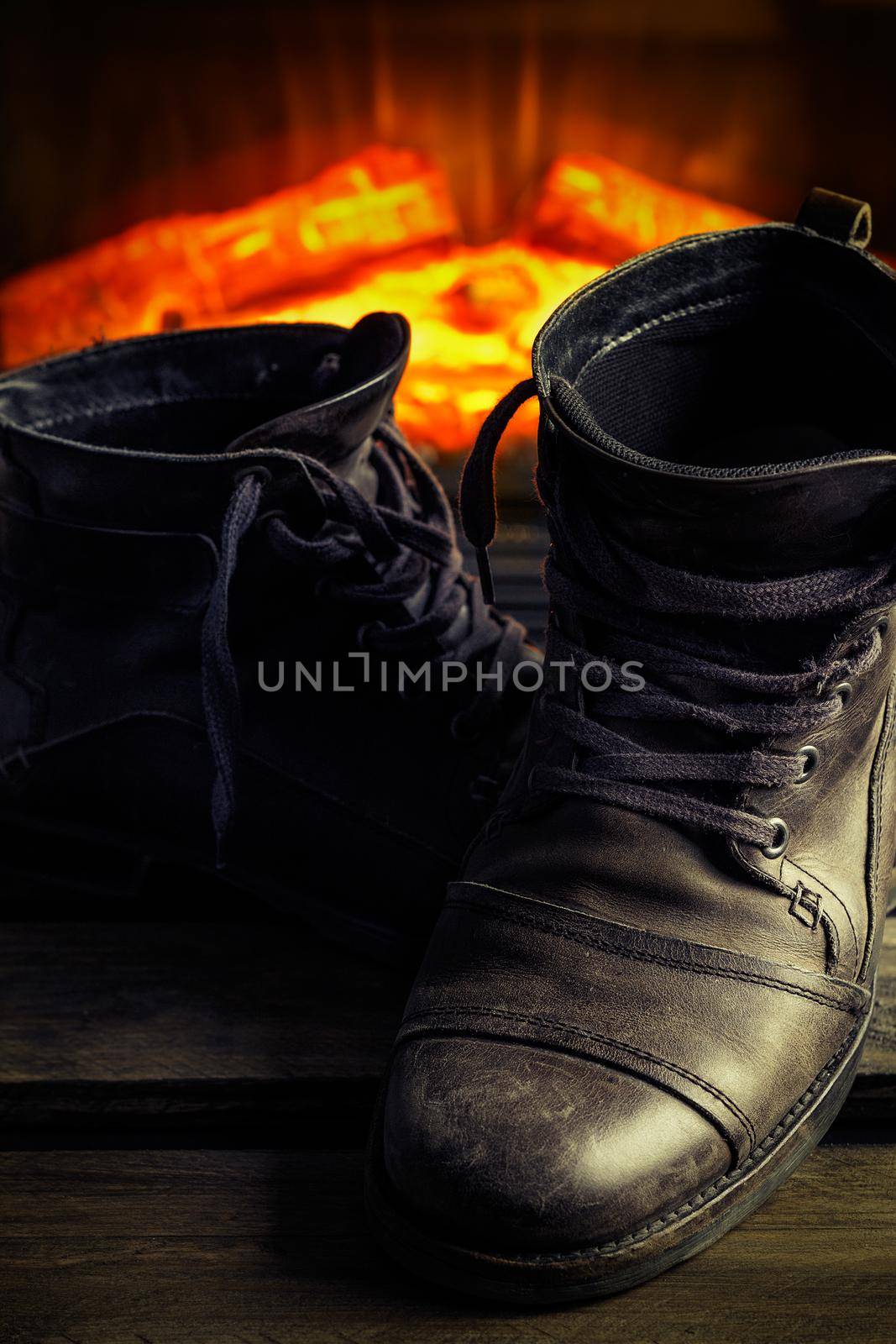 Casual gray leather shoes for men on wooden board with fireplace in the background. Dark mood style. Vertical image.