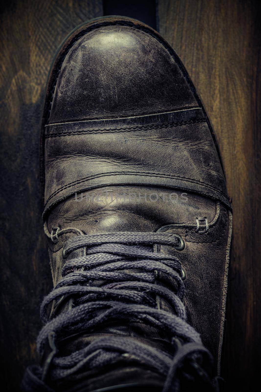 Gray leather casual shoe for man on wooden board. Dark mood style. Top view. Vertical image