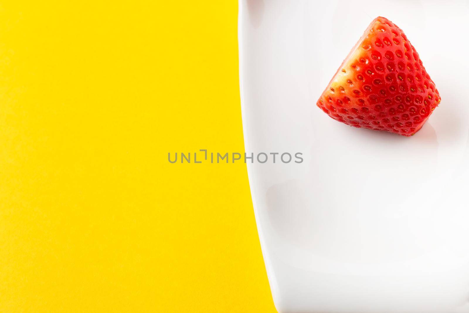 Fresh strawberry in a white dish on yellow background. Horizontal image seen from above.