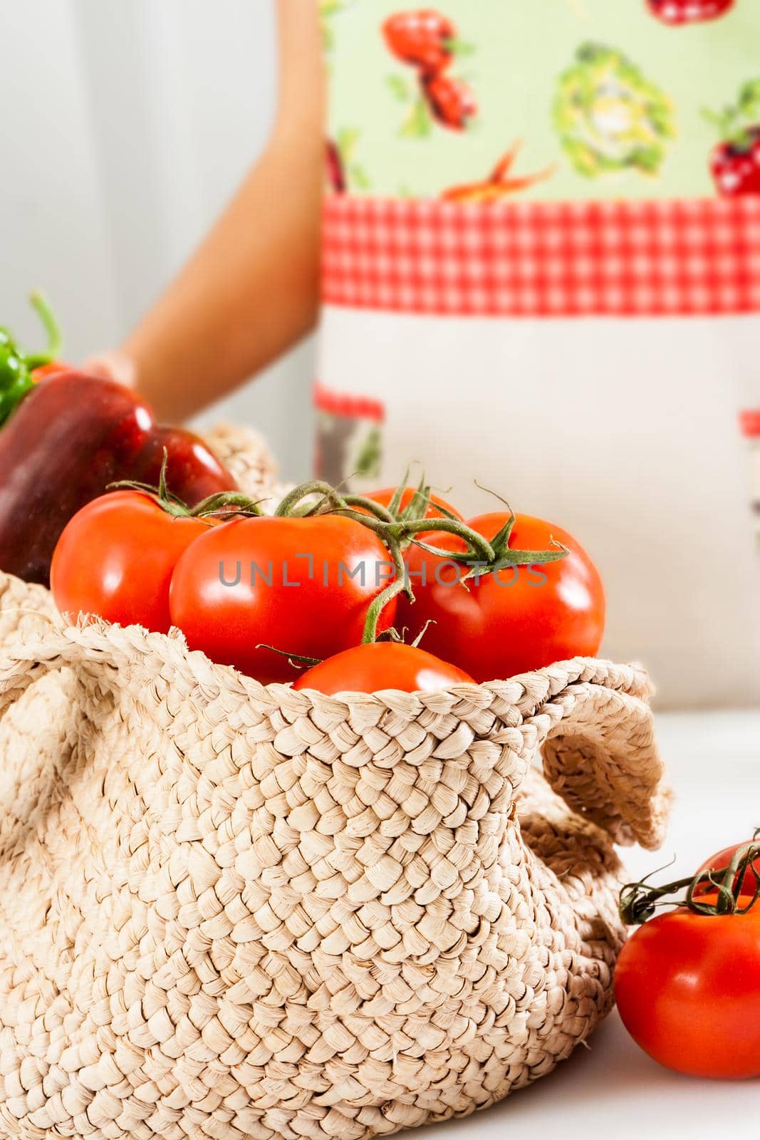 Basket of tomatoes with a woman with an apron in the background