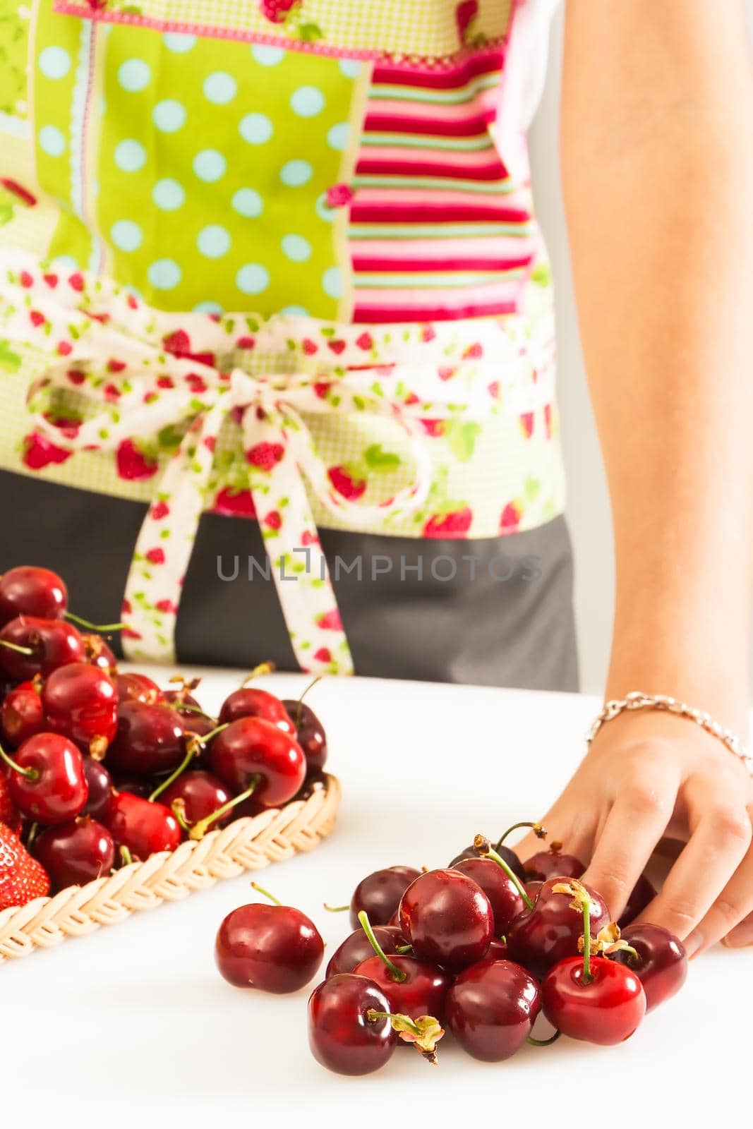 Woman collecting cherries in a wicker tray