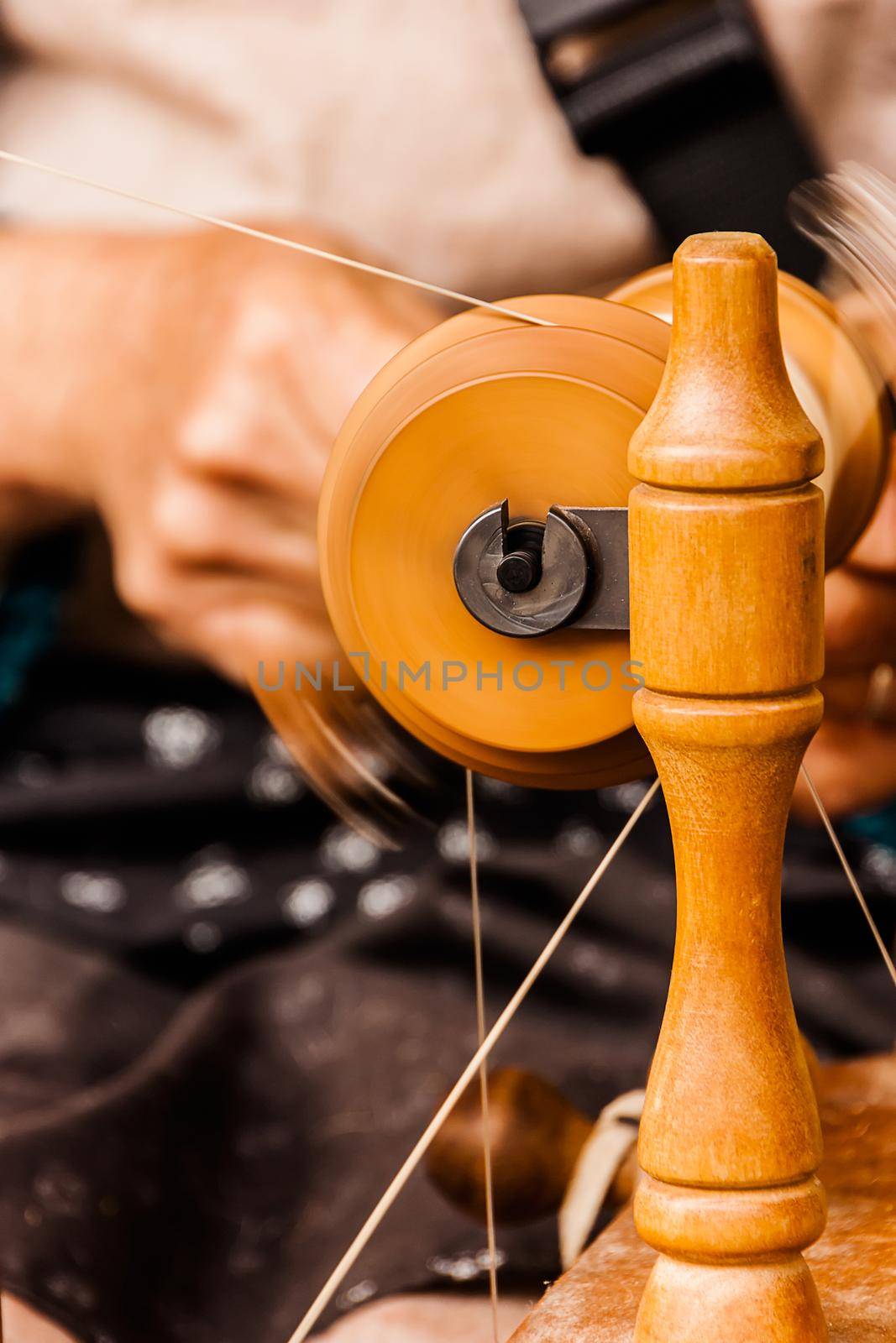 Oldster spinning cotton of traditional form on a craftsmen's market.