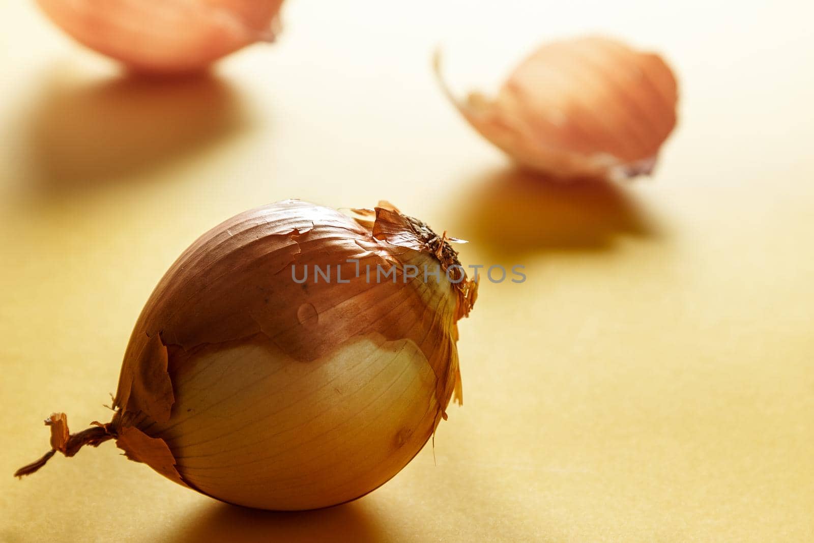 Onion with backlight with onion skins at the bottom on yellow surface. Healthy life concept. Horizontal image.