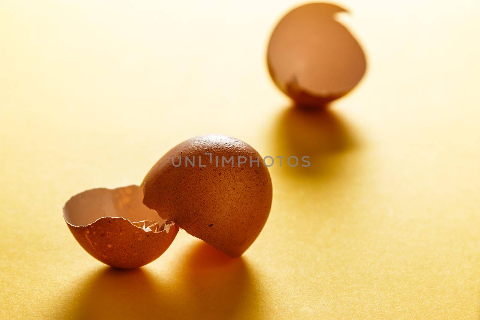Egg shells on yellow surface with more shells in the background. View in the foreground. Food for a healthy life. Horizontal image.