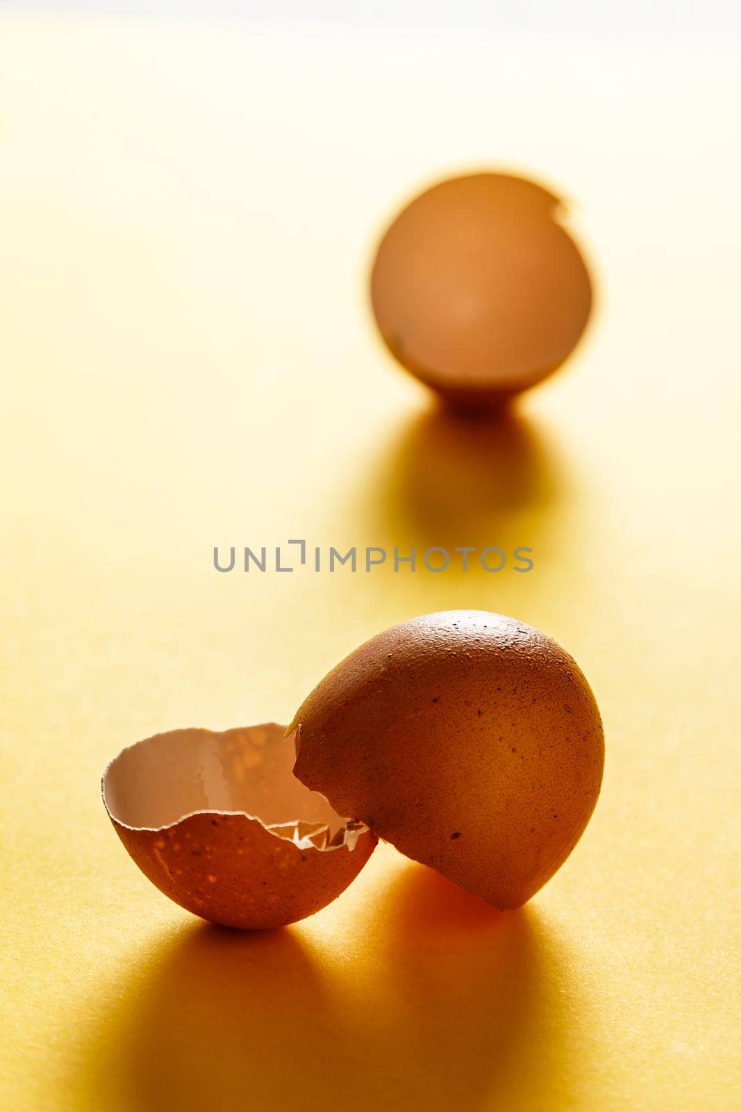 Egg shells on yellow surface with more shells in the background. View in the foreground. Food for a healthy life. Vertical image.