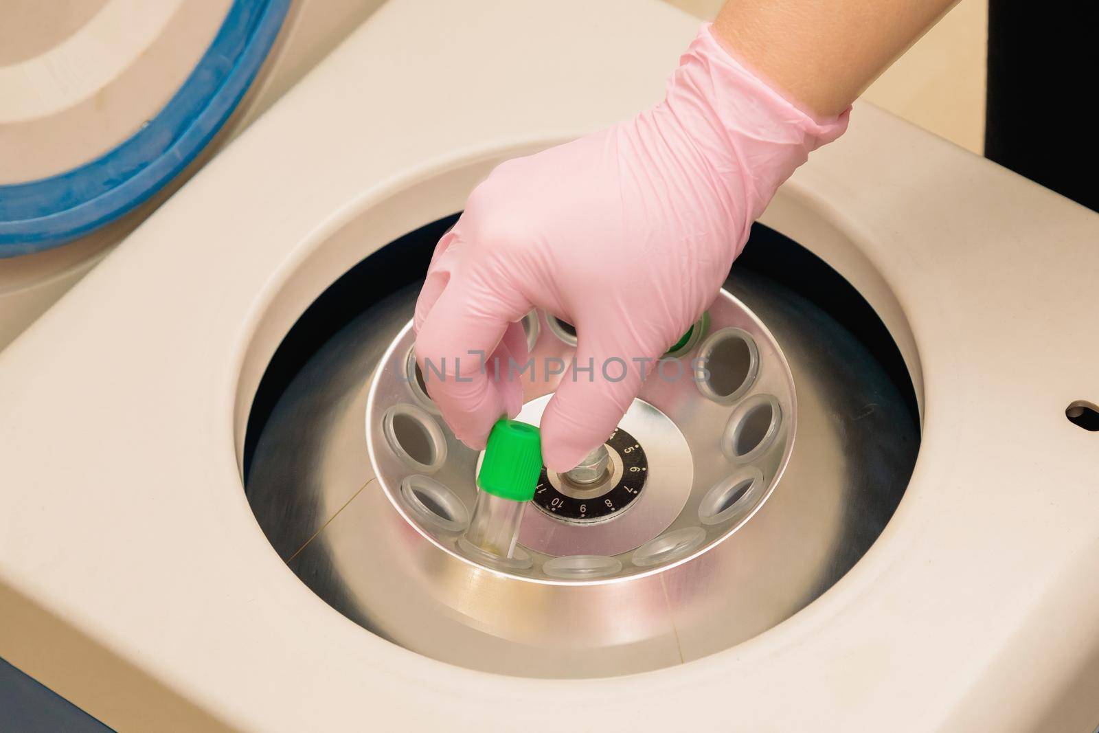 Centrifuge for obtaining blood plasma. The hand of a specialist inserts a test tube into the apparatus.