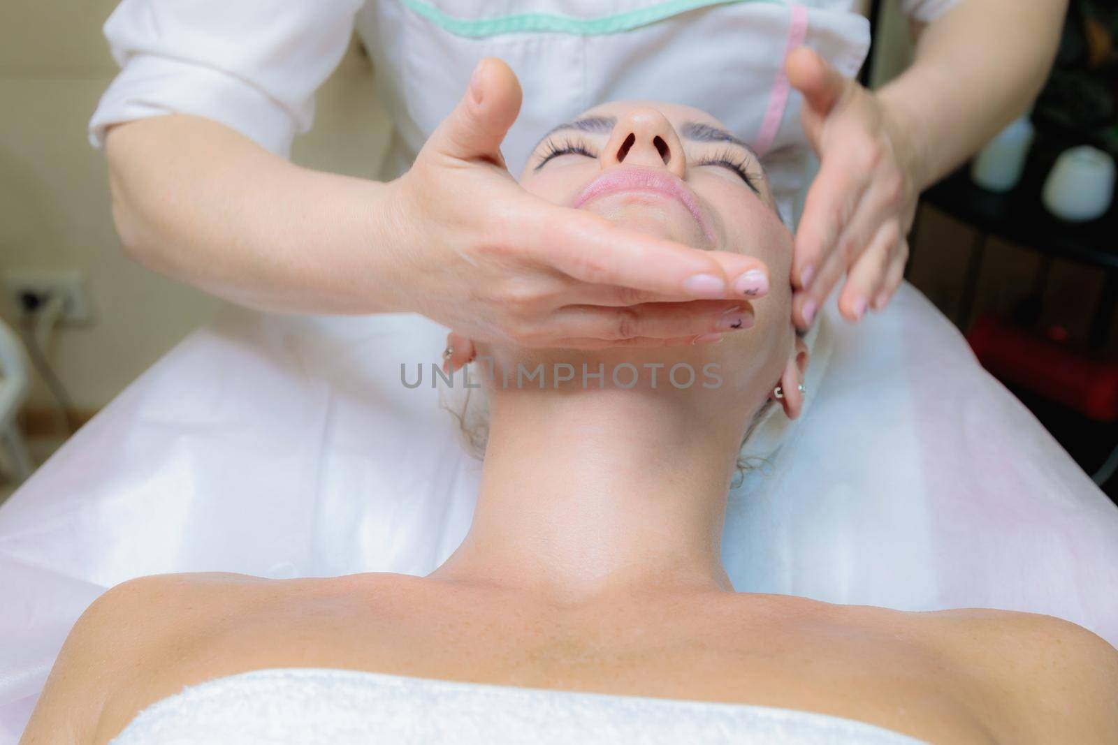 The girl is given a face and neck massage in a beauty salon. by Yurich32