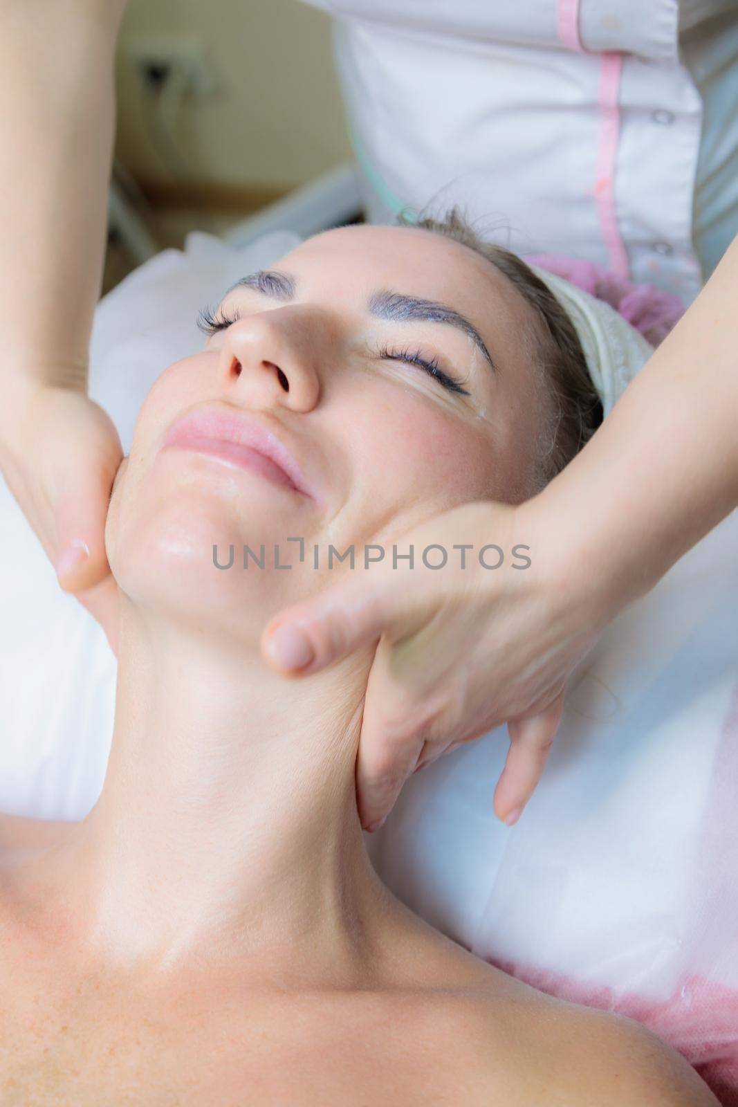 The girl is given a face and neck massage in a beauty salon. Enjoy the procedure