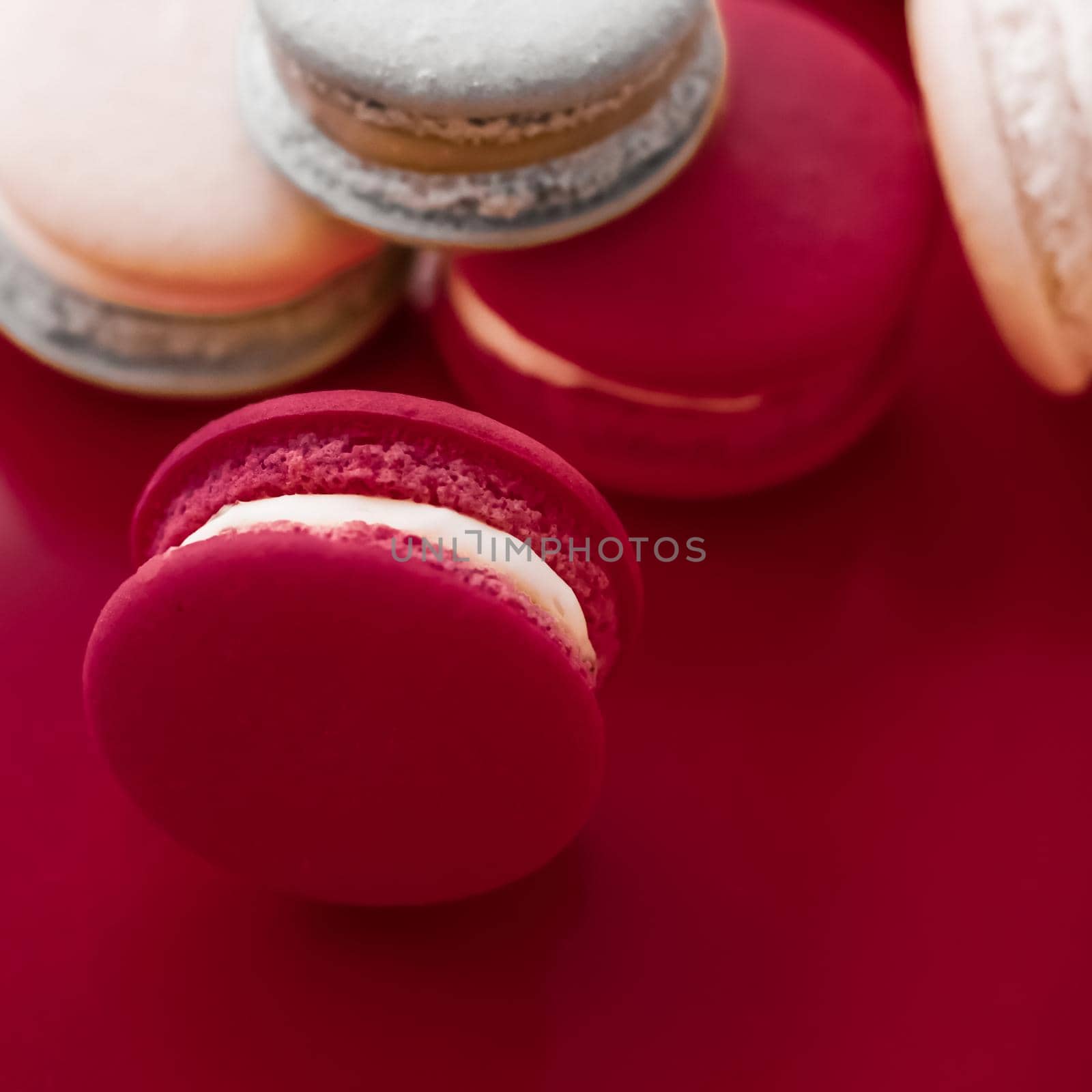 French macaroons on wine red background, parisian chic cafe dessert, sweet food and cake macaron for luxury confectionery brand, holiday backdrop design by Anneleven