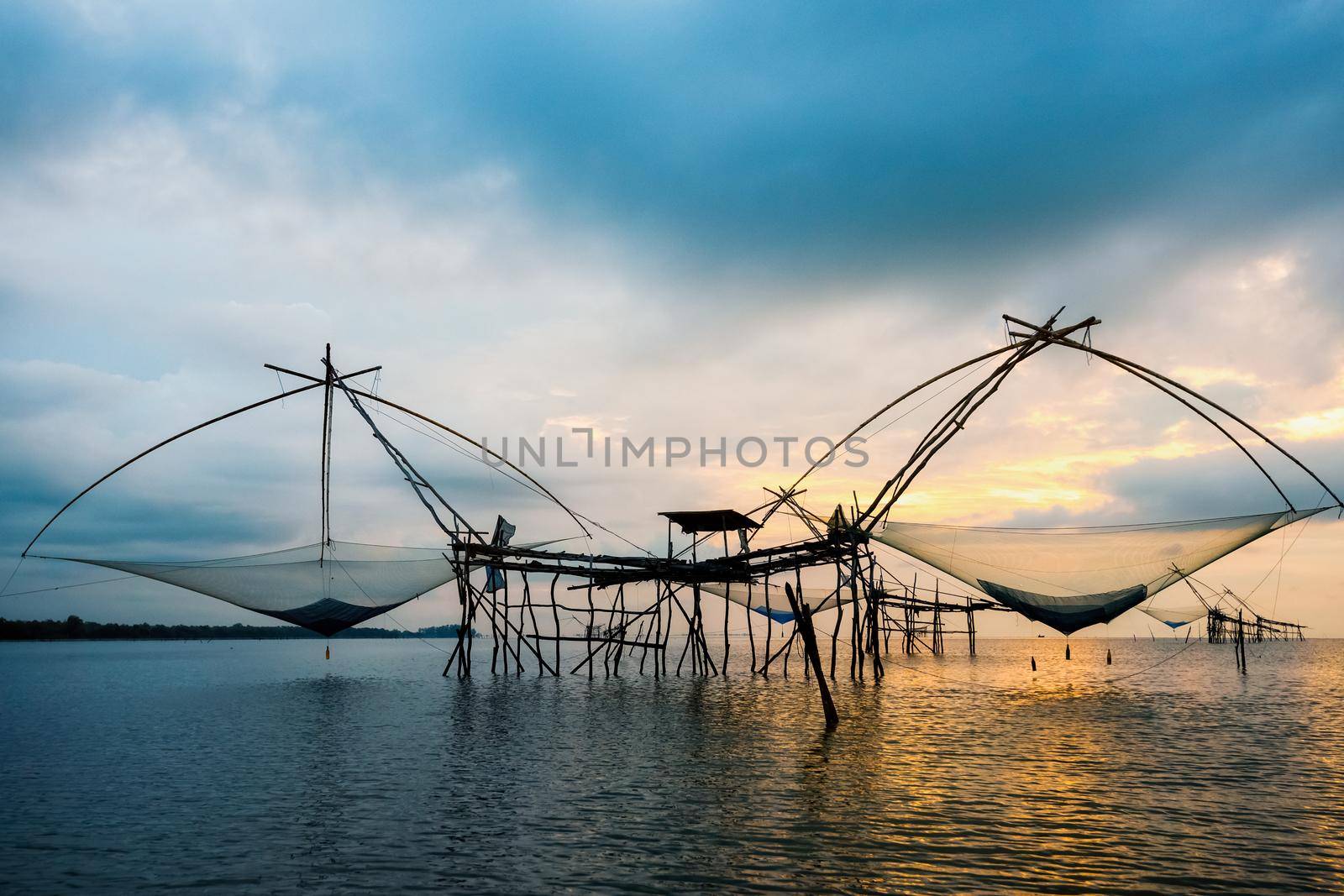 Beautiful nature landscape golden light of the morning sky at sunrise and native fishing tool rural lifestyle at Pakpra canal, Songkhla Lake, Baan Pak Pra is a famous landmark of Phatthalung, Thailand