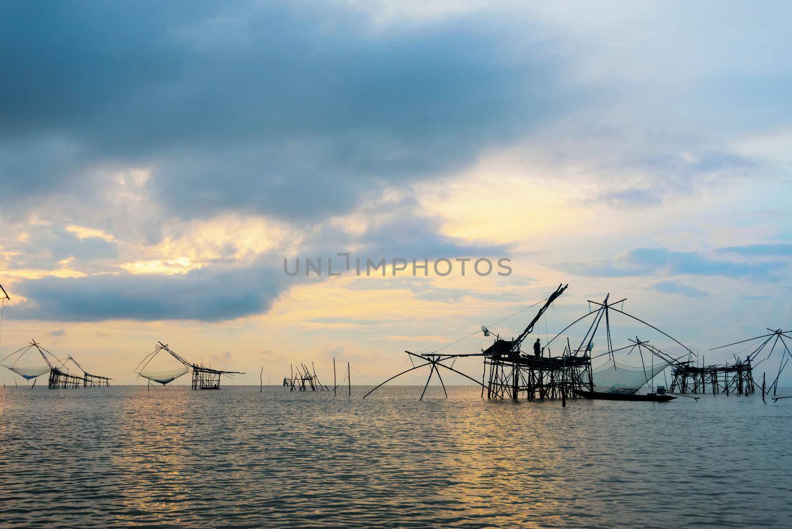 Beautiful nature landscape of Songkhla Lake at sunrise and fisherman are using bamboo and net as native fishing tool to catch fish rural lifestyle at Pakpra canal, Baan Pak Pra, Phatthalung, Thailand