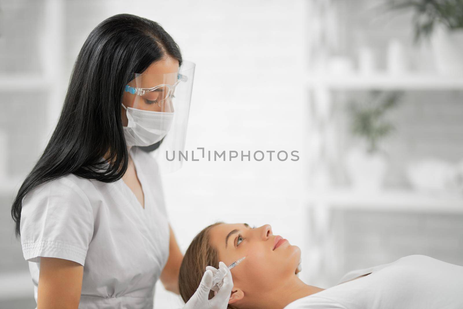 Side view of beautiful beautician in protective mask doing injection tighten skin from wrinkles in professional beautician. Concept of process injection for improve the condition face. 