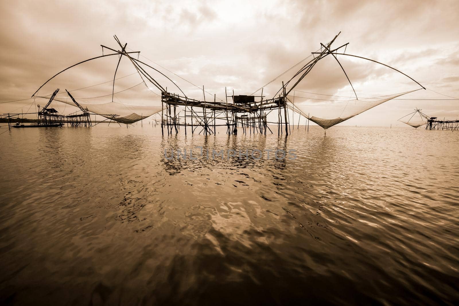 Old photo in sepia warm two tone vintage style, landscapes of Songkhla Lake and fishing square dip net is a local fishing tool rural lifestyle at Pakpra canal, Baan Pak Pra, Phatthalung in Thailand