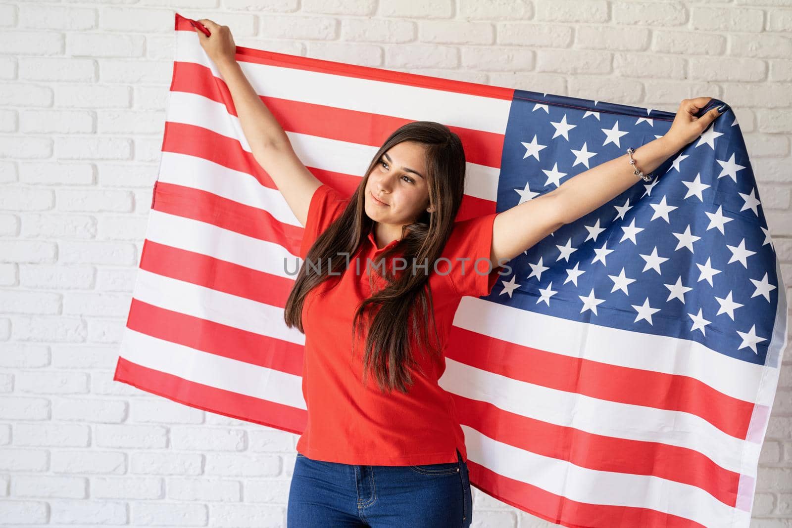 Independence day of the USA. Happy July 4th. Young smiling woman with national flag of the USA.