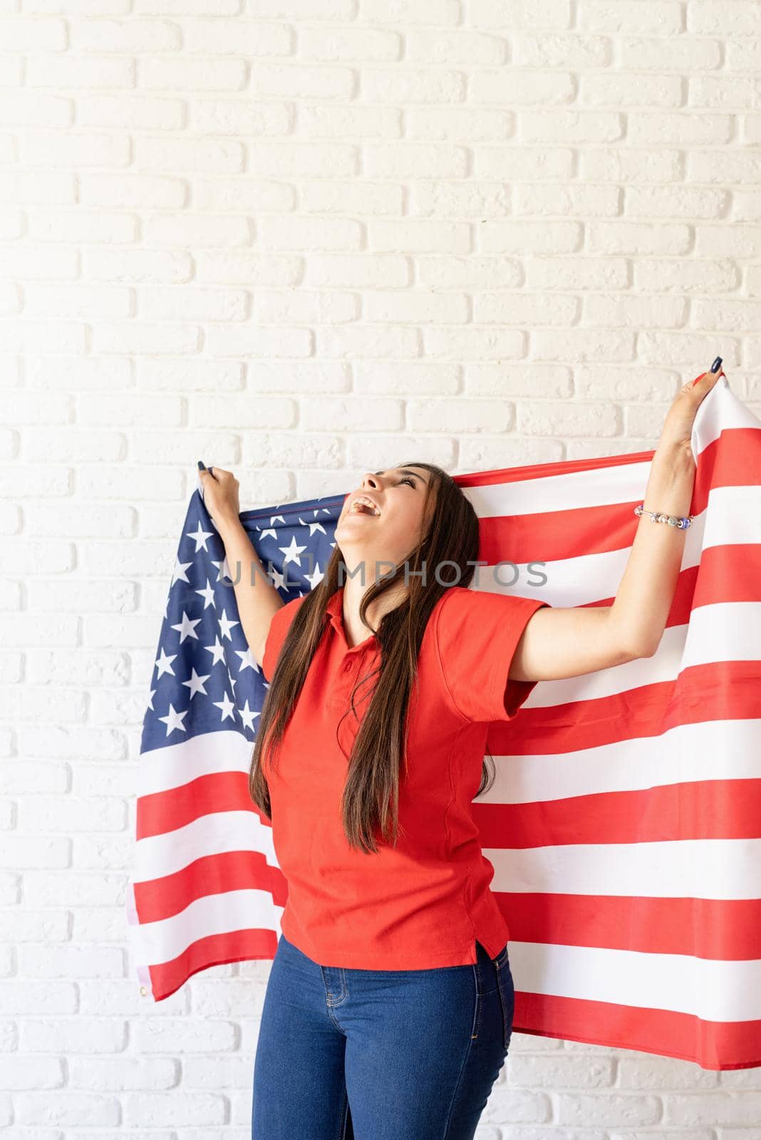 beautiful young laughing woman with american flag, arms outstretched by Desperada