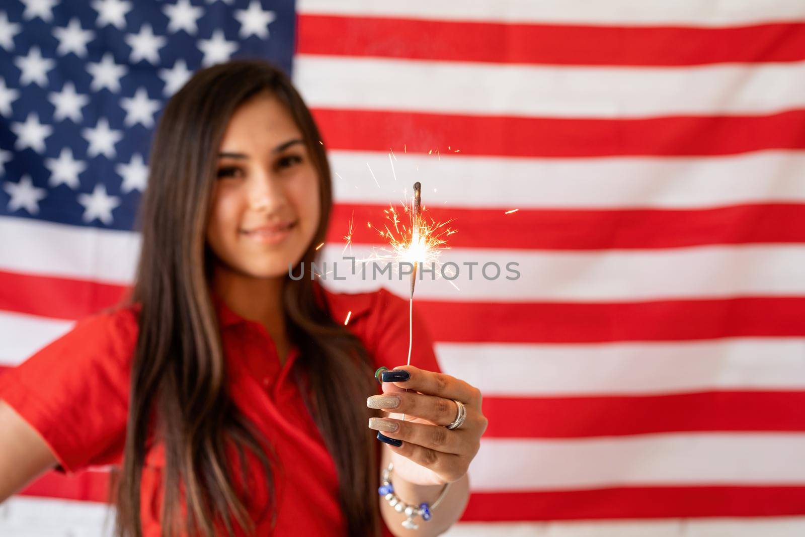 Beautiful woman holding a sparkler on the USA flag background by Desperada