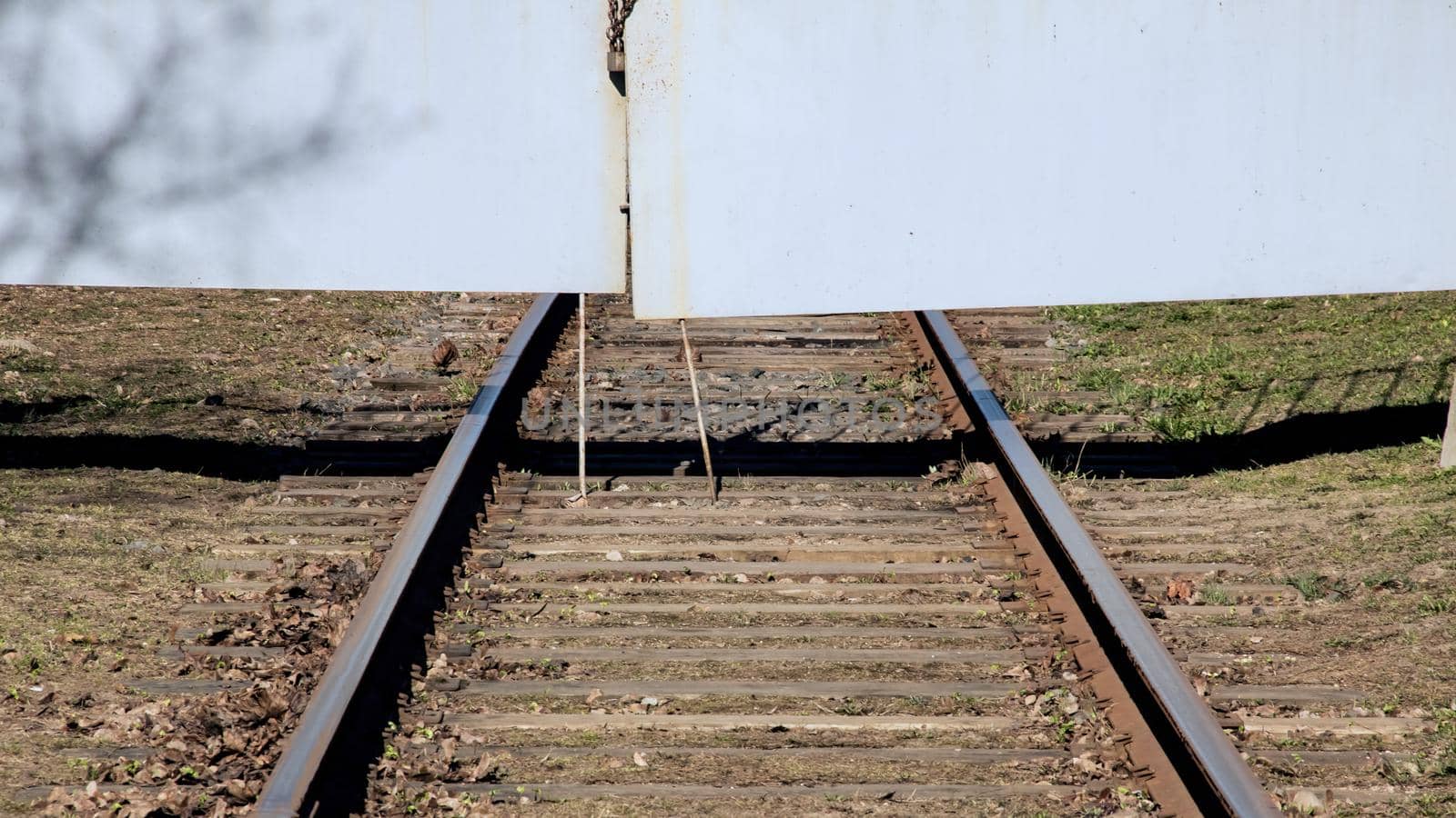 Railway rests against the meallic gate close up, green grass