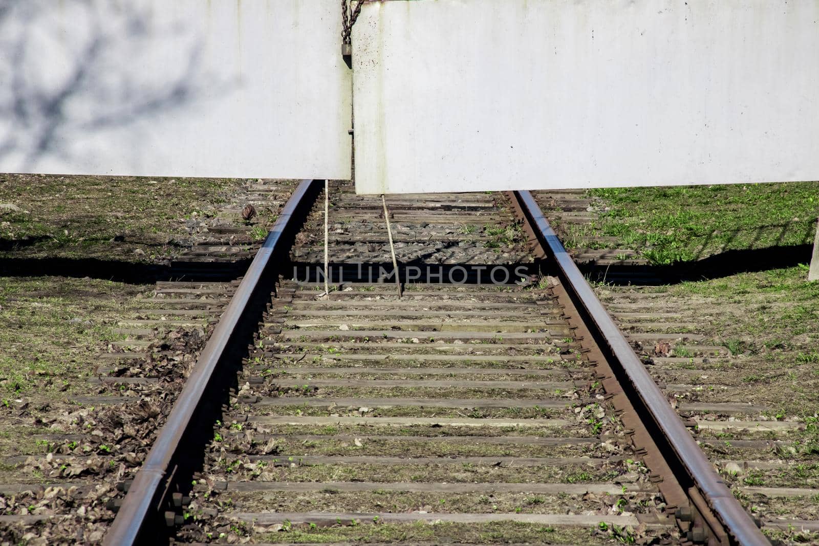 Railway rests against the meallic gate close up, green grass