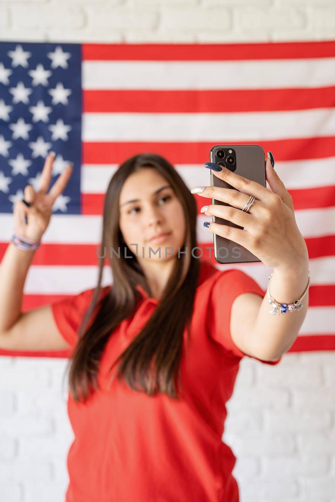 Independence day of the USA. Happy July 4th. Beautiful woman taking a selfie on the USA flag background