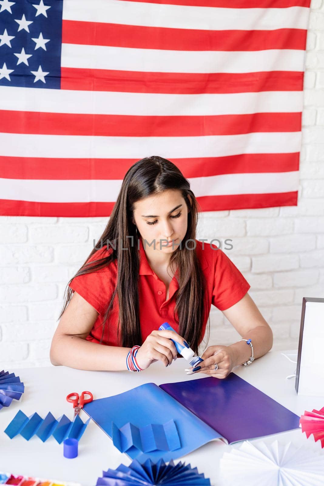 Independence day of the USA. Happy July 4th. Beautiful woman making DIY paper fans of red and blue colors to celebrate July 4th