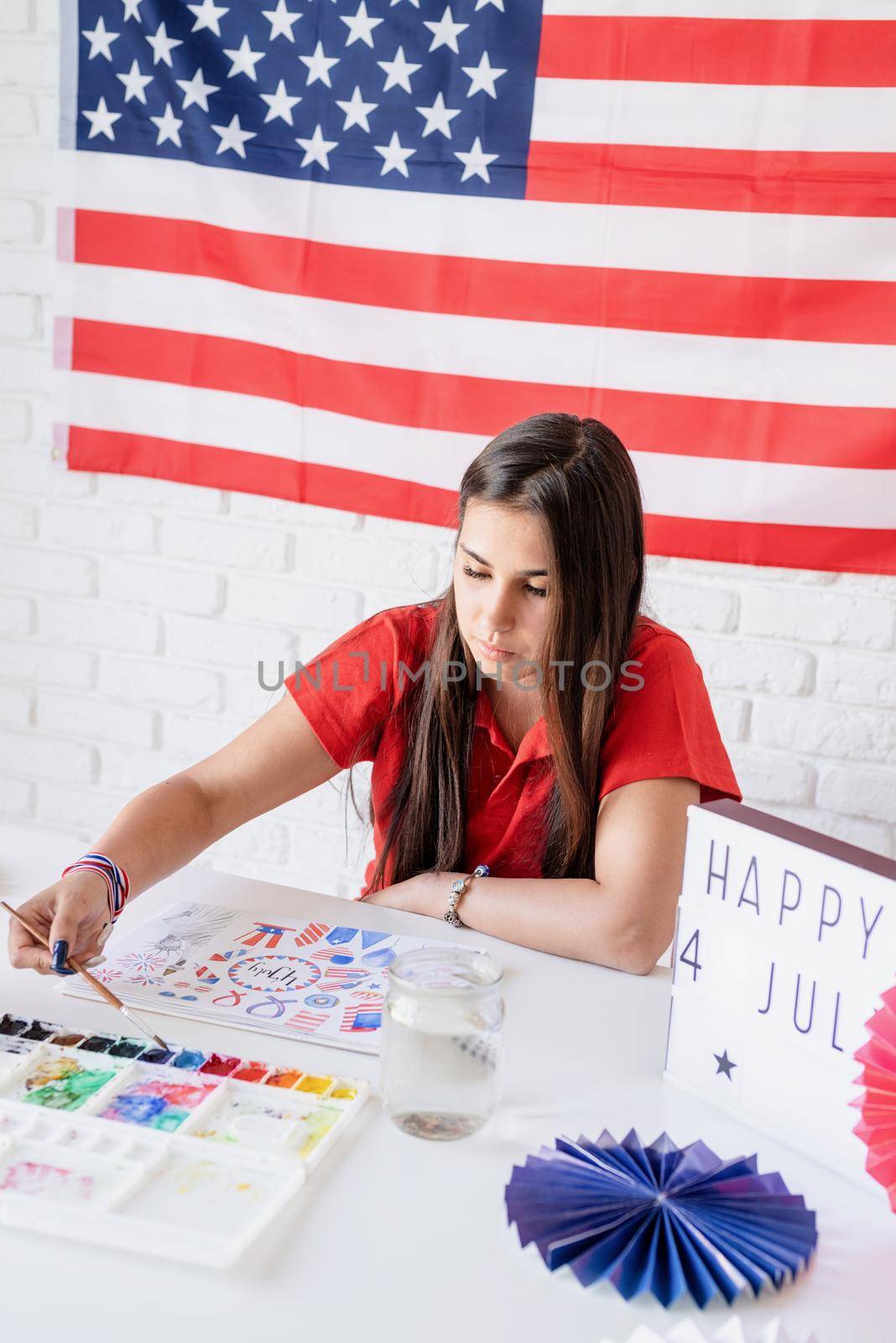 Independence day of the USA. Happy July 4th. Beautiful woman drawing a watercolor illustration for Independence day of the USA. Happy 4 July the text on the lightbox