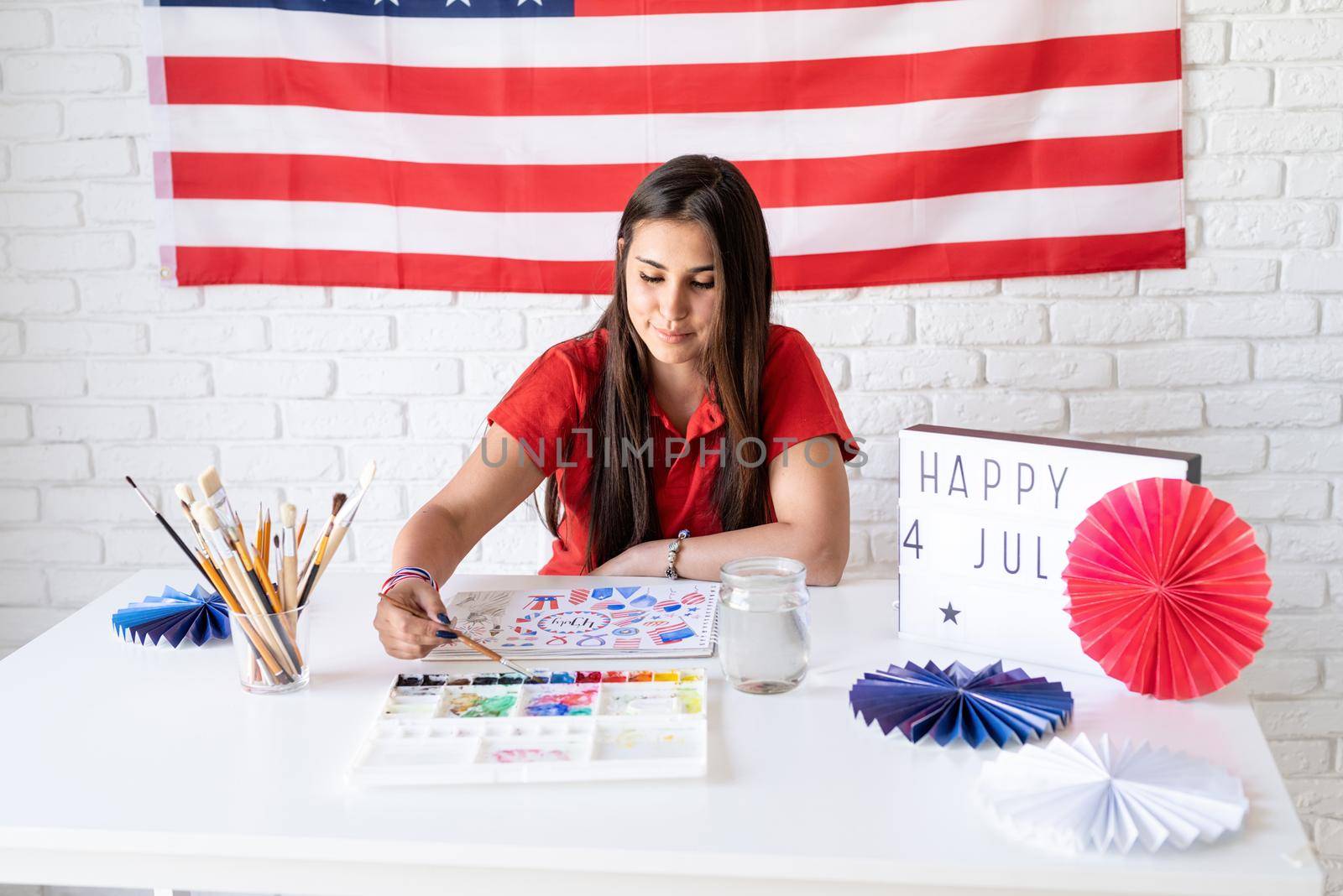 Independence day of the USA. Happy July 4th. Beautiful woman drawing a watercolor illustration for Independence day of the USA. Happy 4 July the text on the lightbox