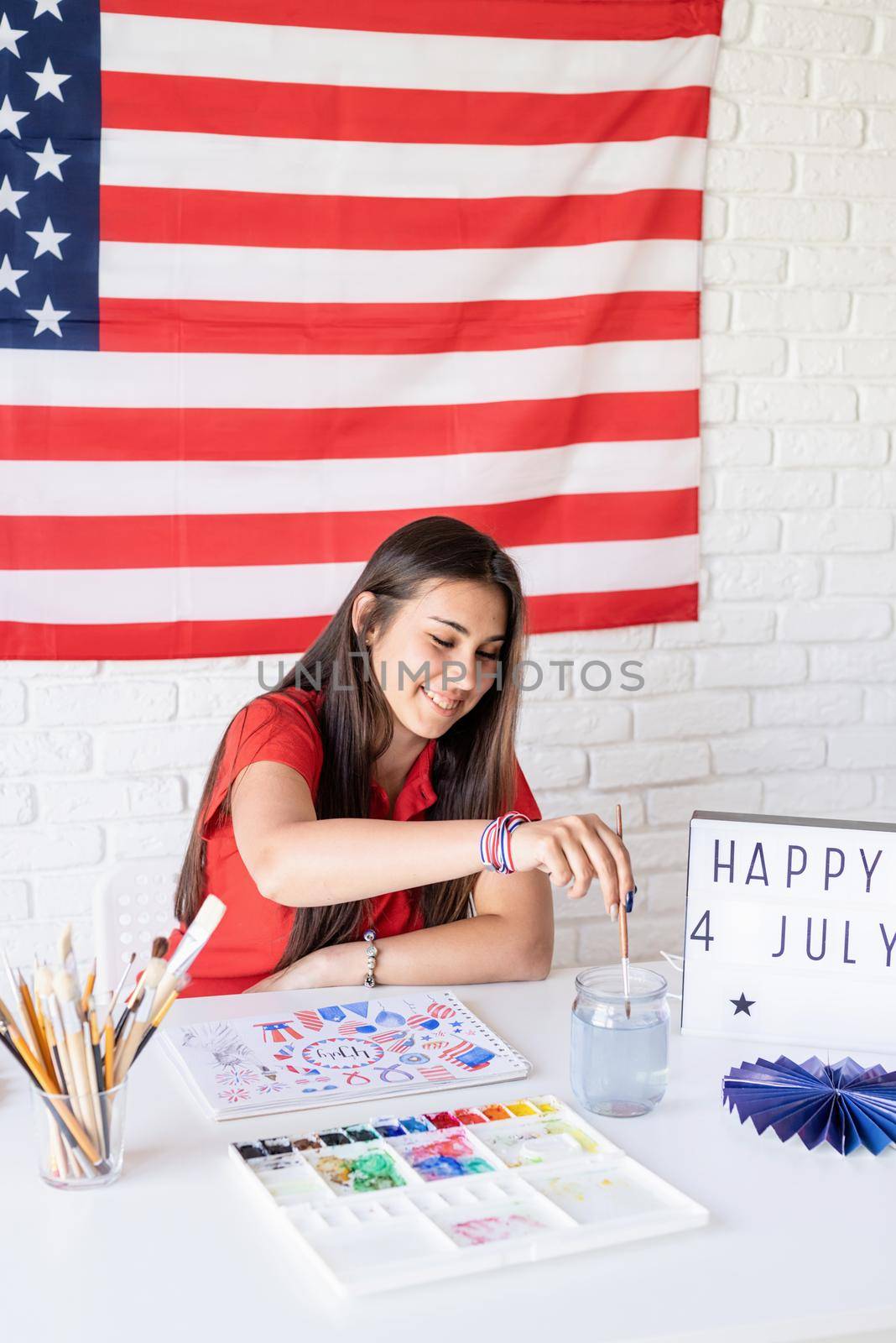Independence day of the USA. Happy July 4th. Beautiful woman drawing a watercolor illustration for Independence day of the USA. Happy 4 July the text on the lightbox