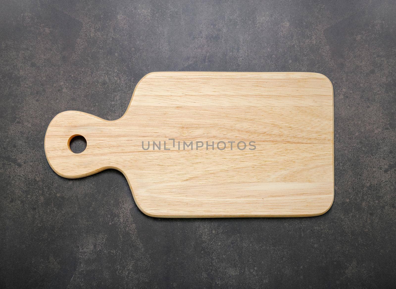 Empty vintage wooden cutting board set up on dark concrete background with copy space.