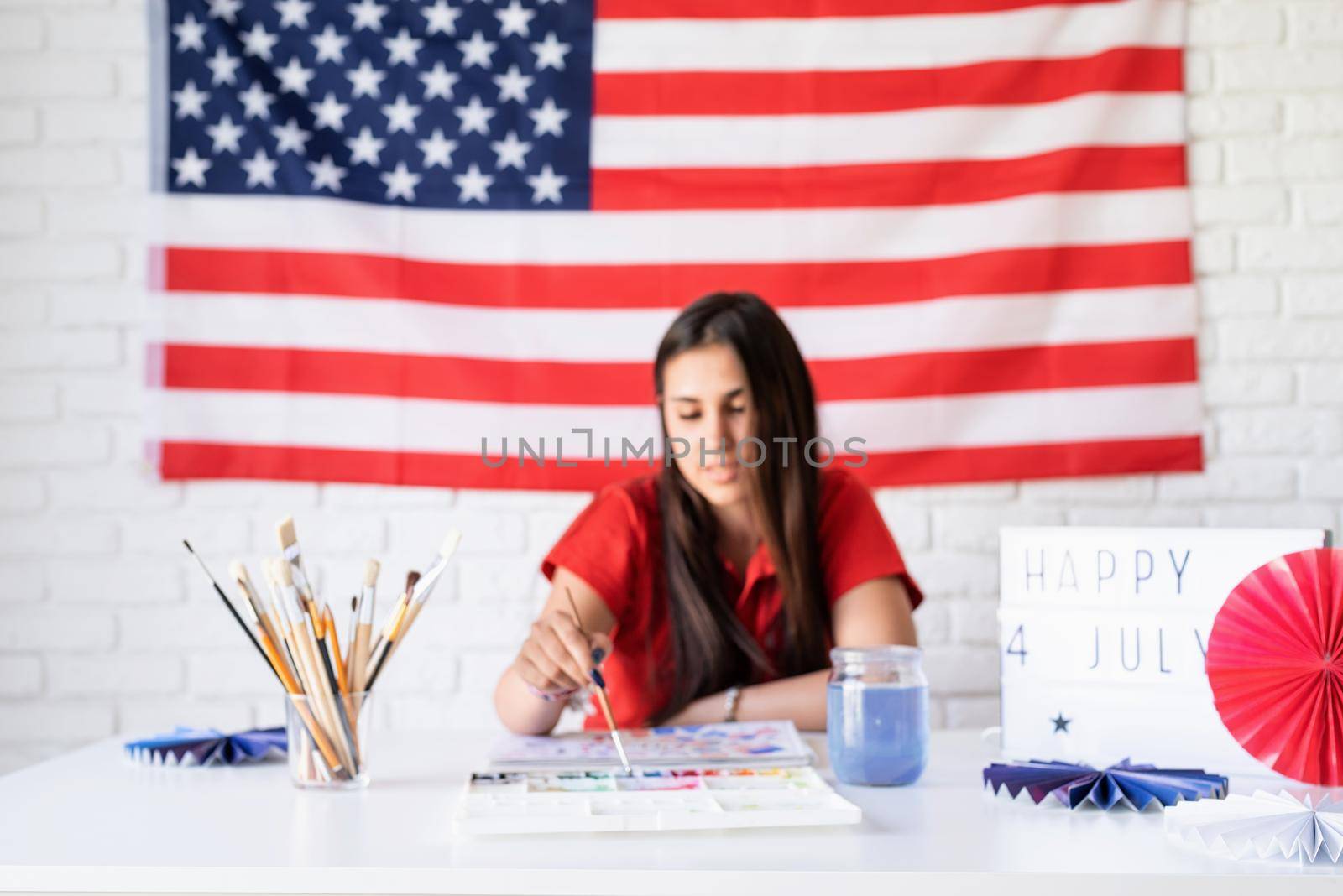 Independence day of the USA. Happy July 4th. Beautiful woman drawing a watercolor illustration for Independence day of the USA, selective focus, focus on foreground. Happy 4 July the text on the lightbox