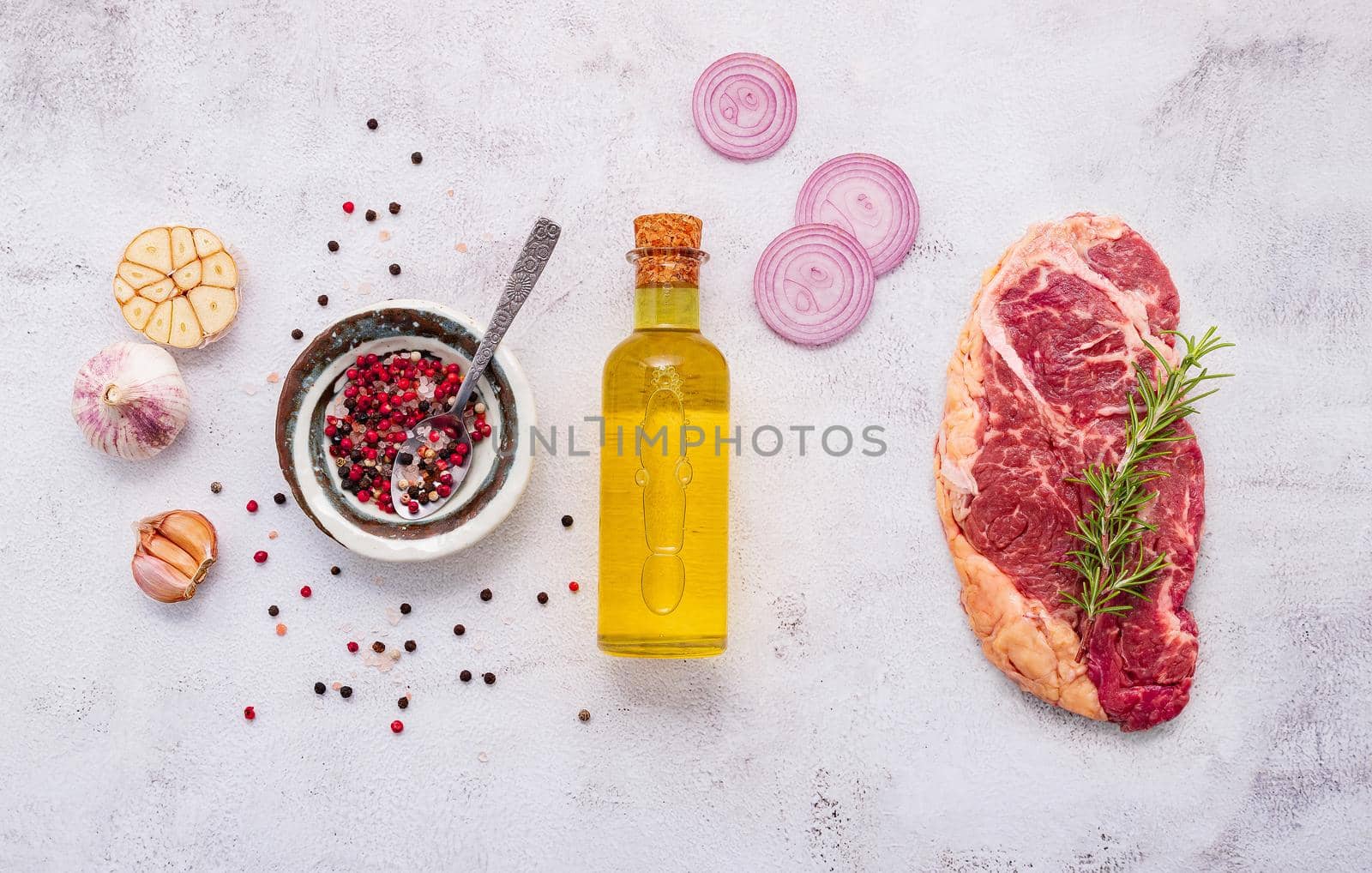 Raw Striplion Steak set up on white concrete background. Flat Lay of fresh raw beef steak with rosemary and spice on white shabby concrete background top view.