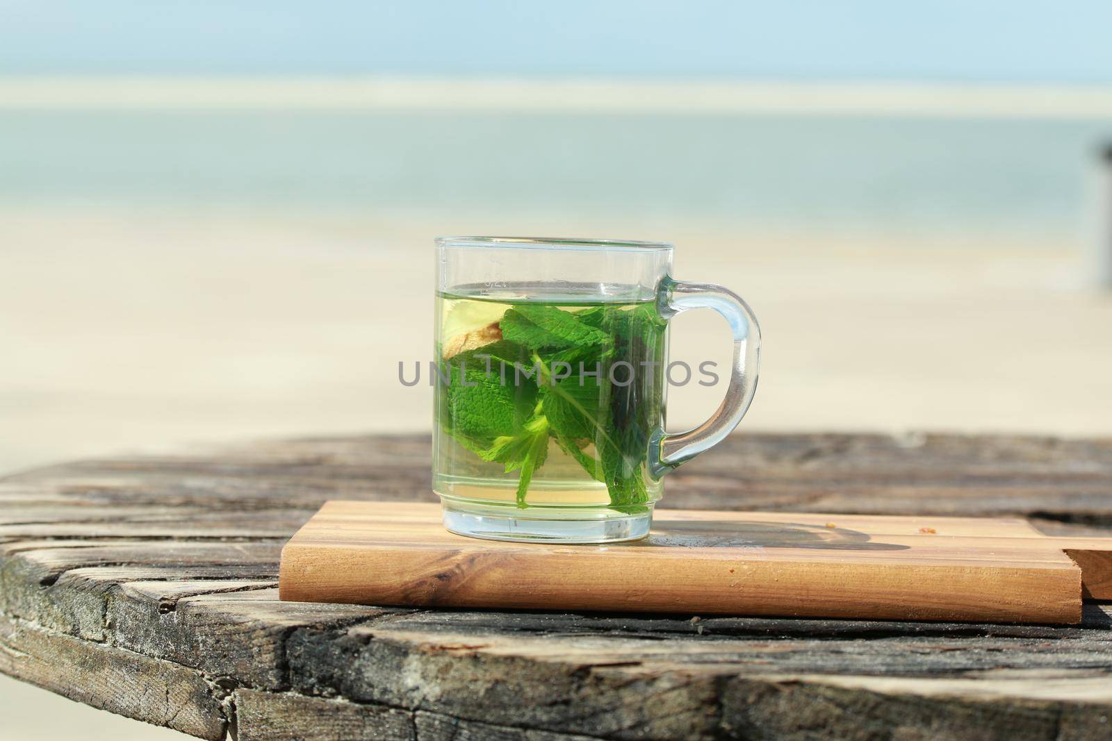 Peppermint tea with green leaves in front of a beach by Luise123