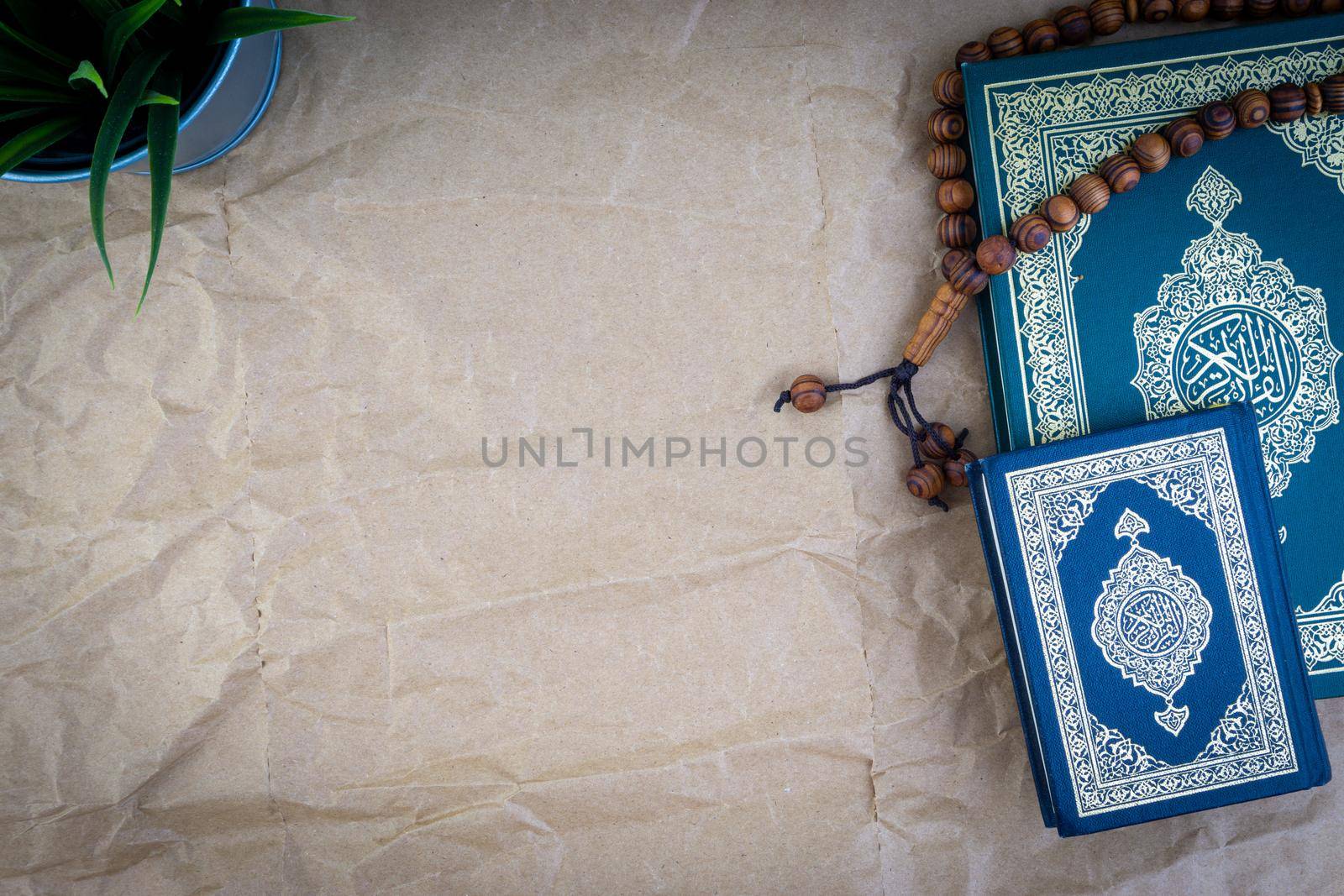 Holy Quran with arabic calligraphy meaning of Al Quran and tasbih or rosary beads over wooden paper background by silverwings