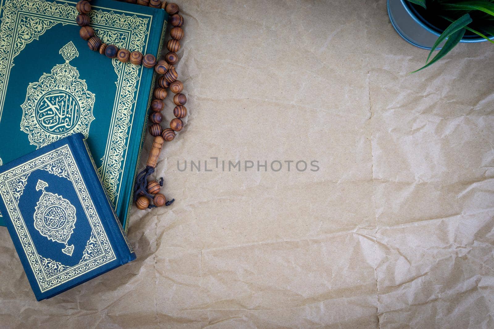 Holy Quran with arabic calligraphy meaning of Al Quran and tasbih or rosary beads over wooden paper background by silverwings
