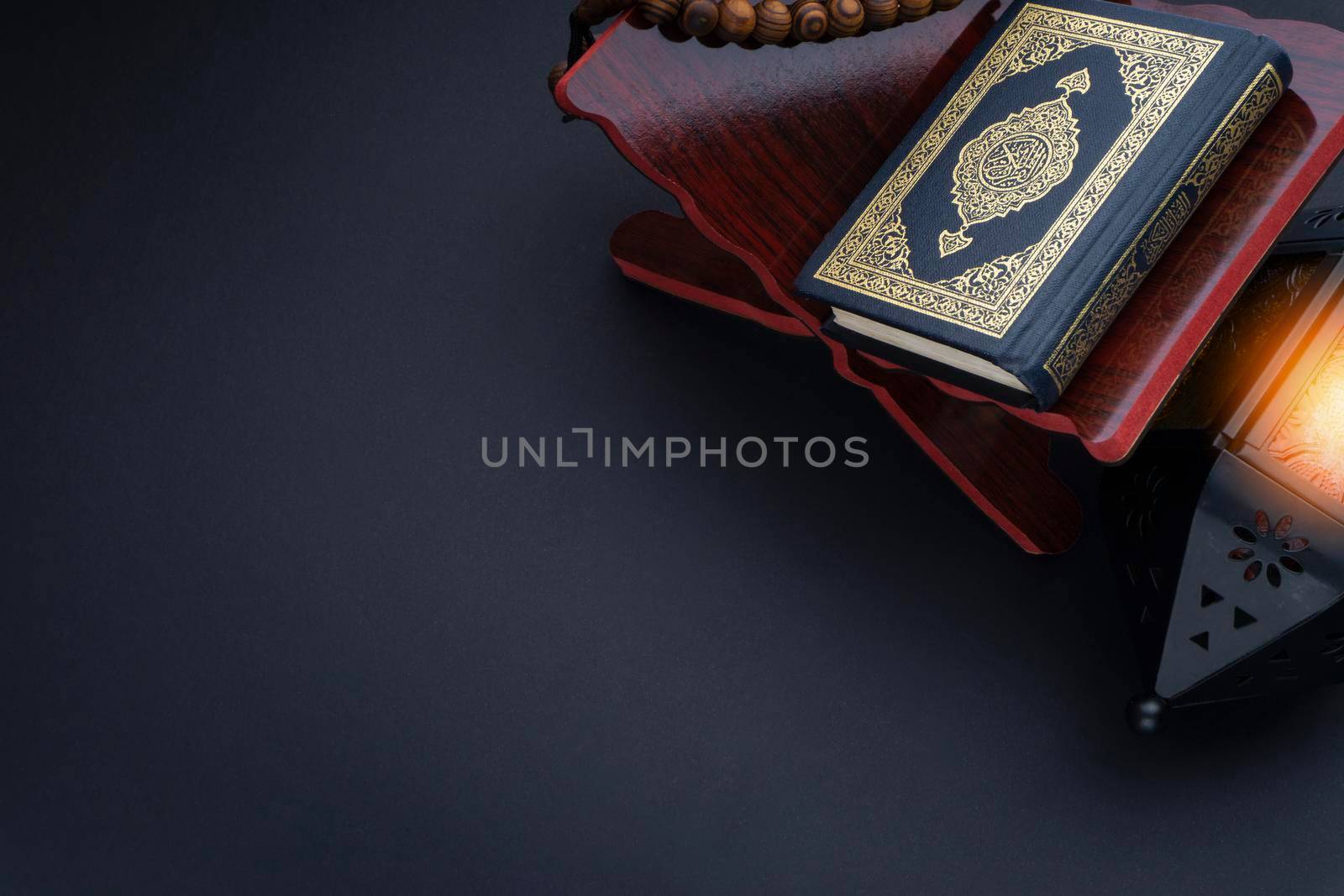 Holy Al Quran with written arabic calligraphy meaning of Al Quran, lantern lamp and rosary beads or tasbih on black background. by silverwings