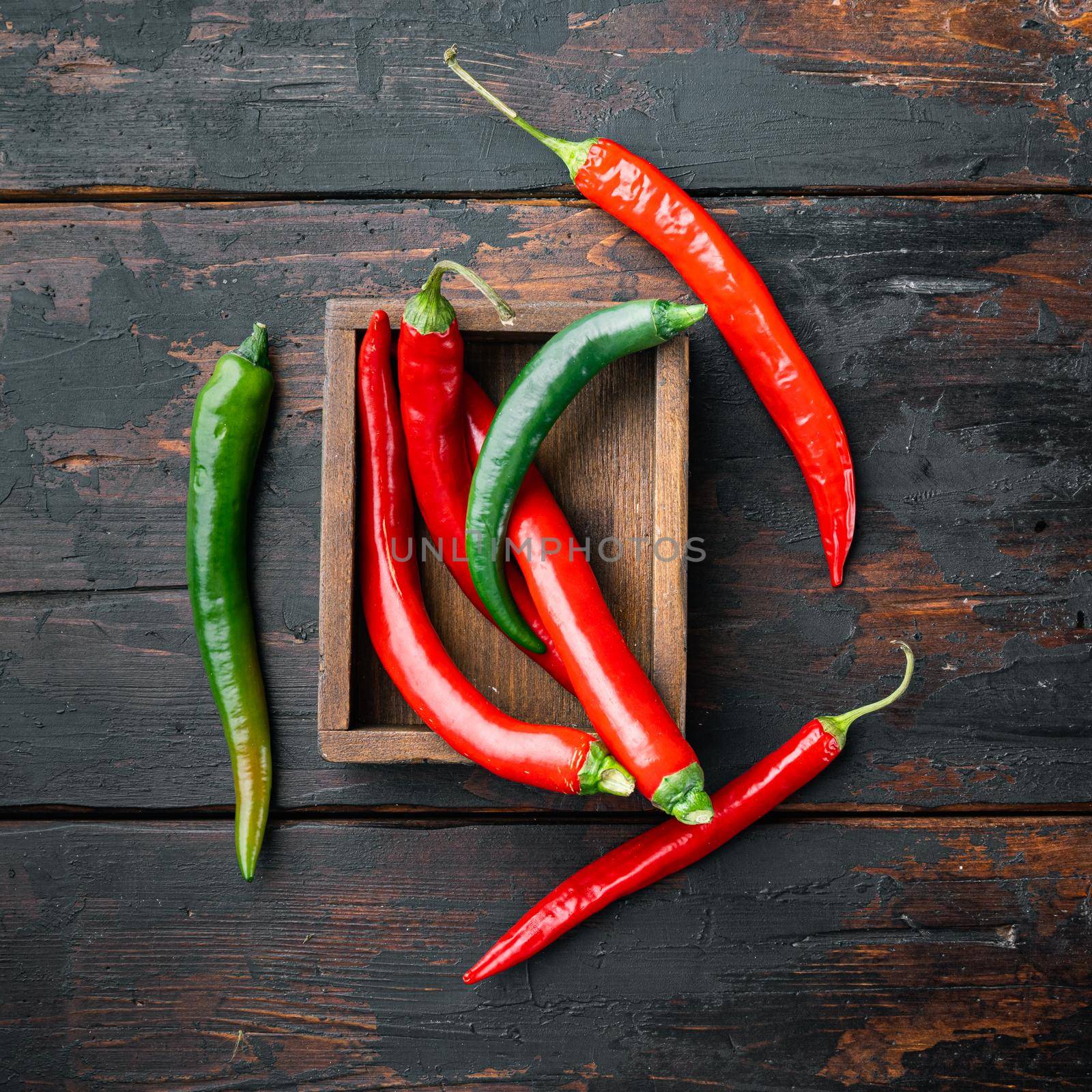 Red and green chili pepper, in wooden box, on dark wooden background, top view flat lay by Ilianesolenyi