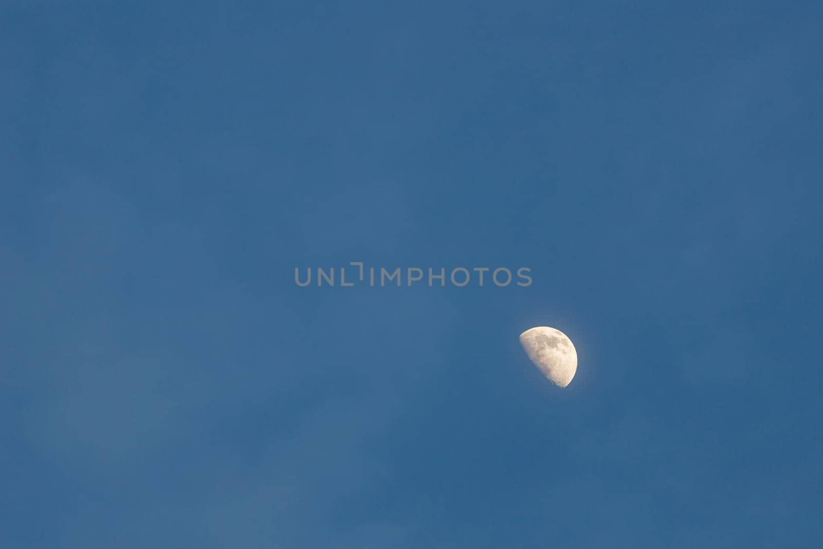 Half-moon in evening sky with faint clouds by colintemple