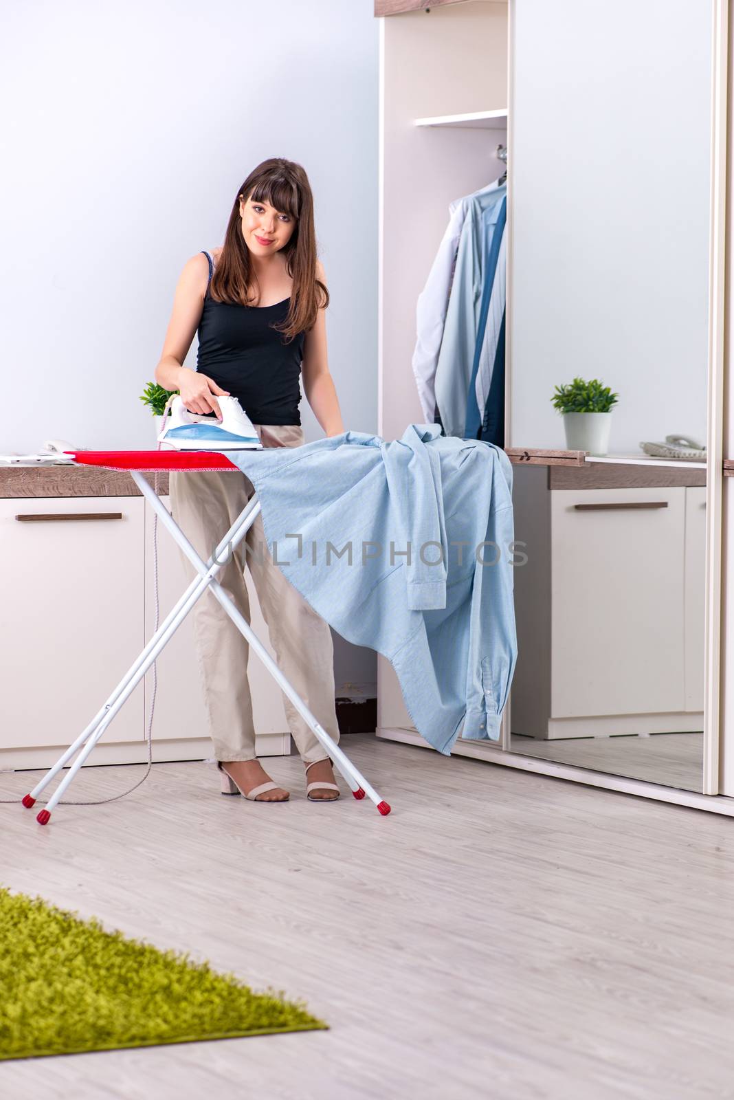 Young woman ironing in the bedroom for husband