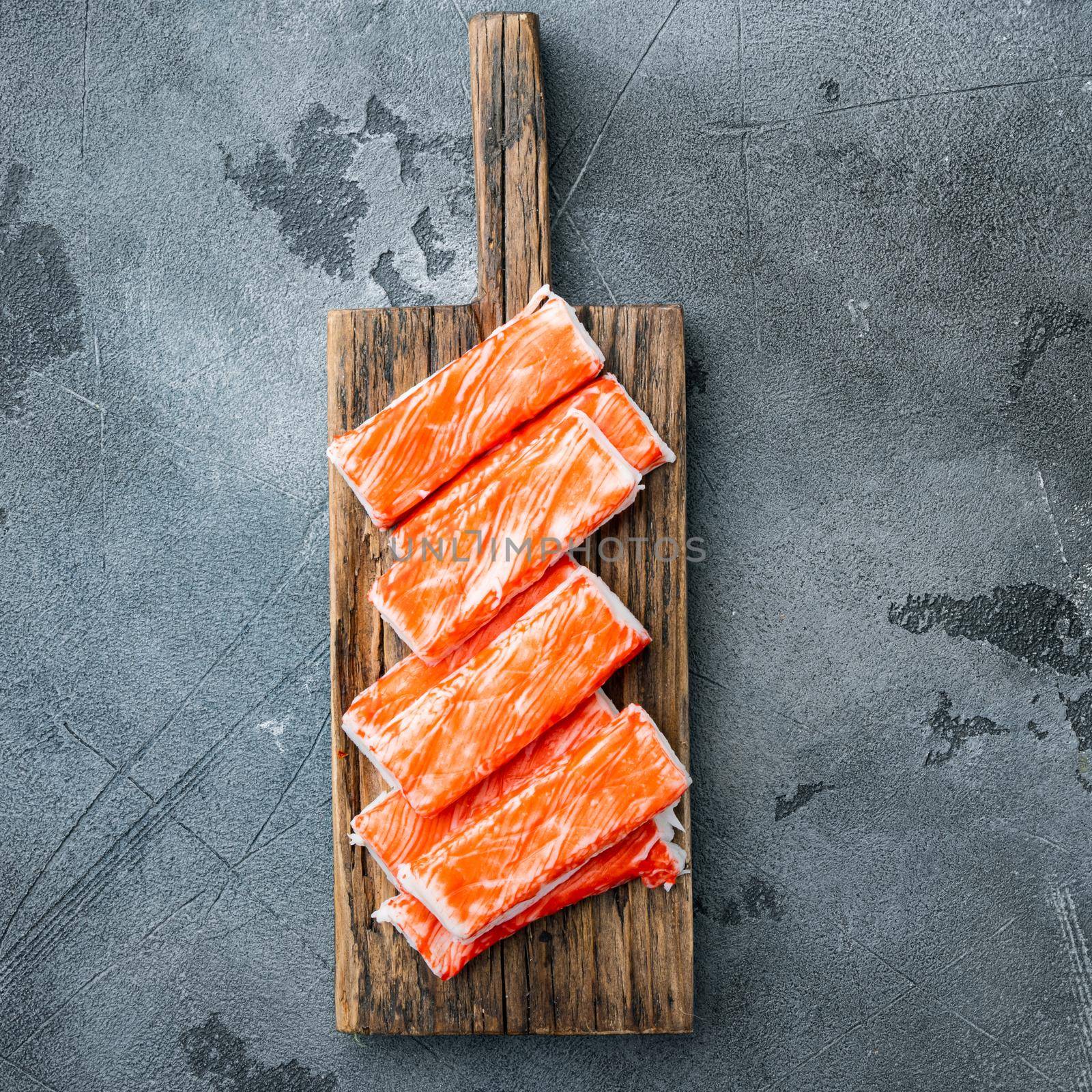 Fresh Crab meat stick surimi with blue swimming crab, on wooden cutting board, on gray background, top view flat lay by Ilianesolenyi